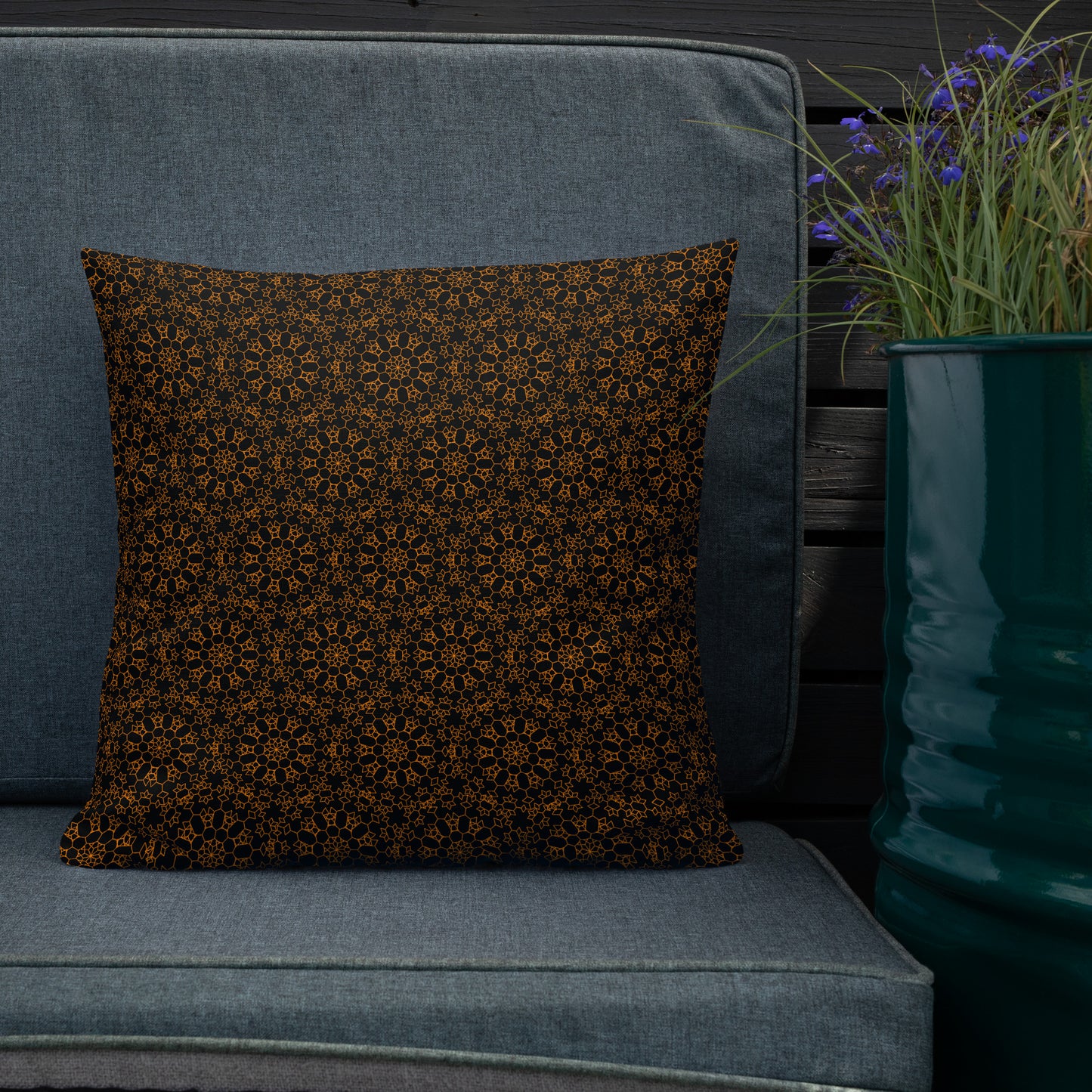 18″×18″ premium throw pillow with the 'Enneagon' black & gold geometric pattern on an outdoor sofa with dark slat wall.