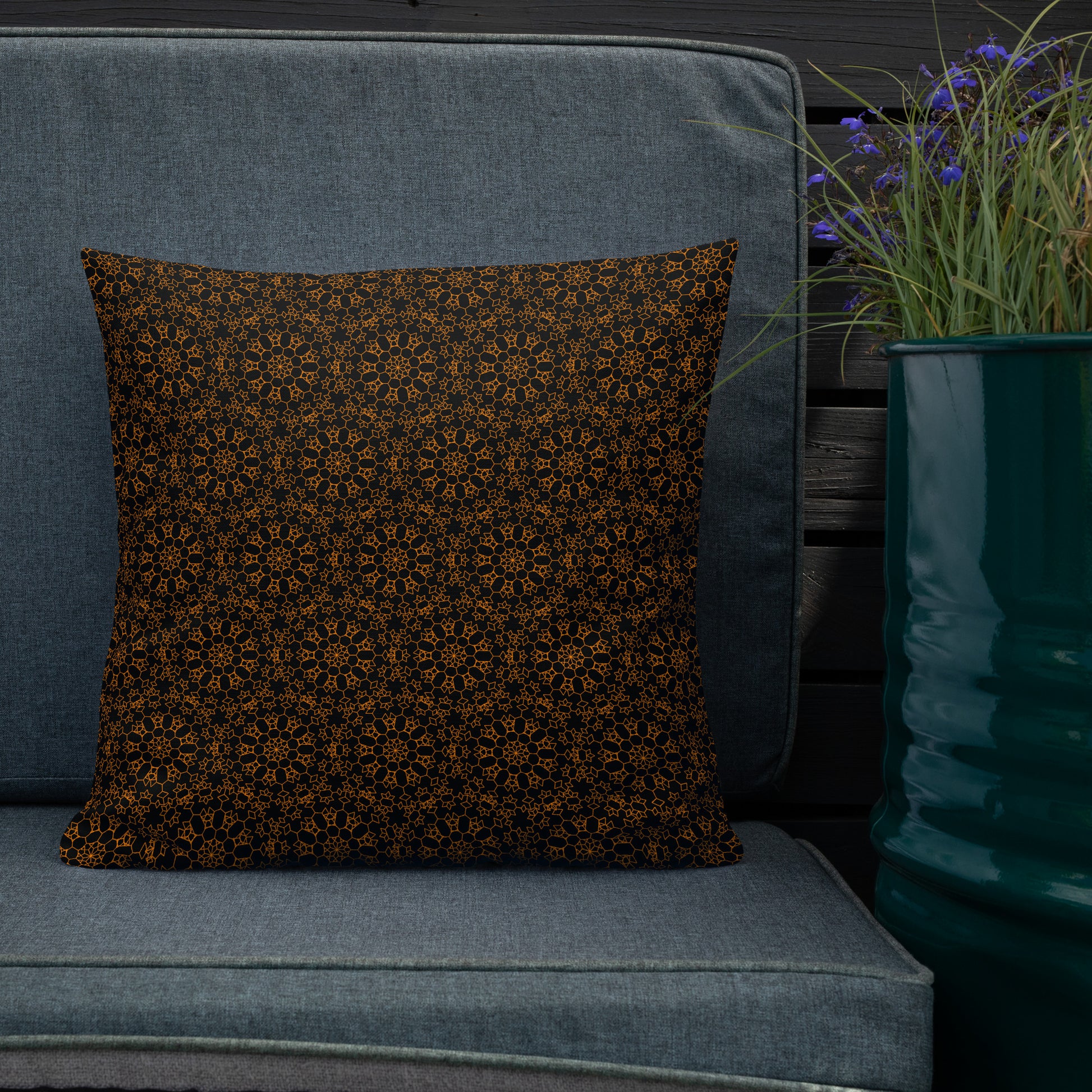 18″×18″ premium throw pillow with the 'Enneagon' black & gold geometric pattern on an outdoor sofa with dark slat wall.