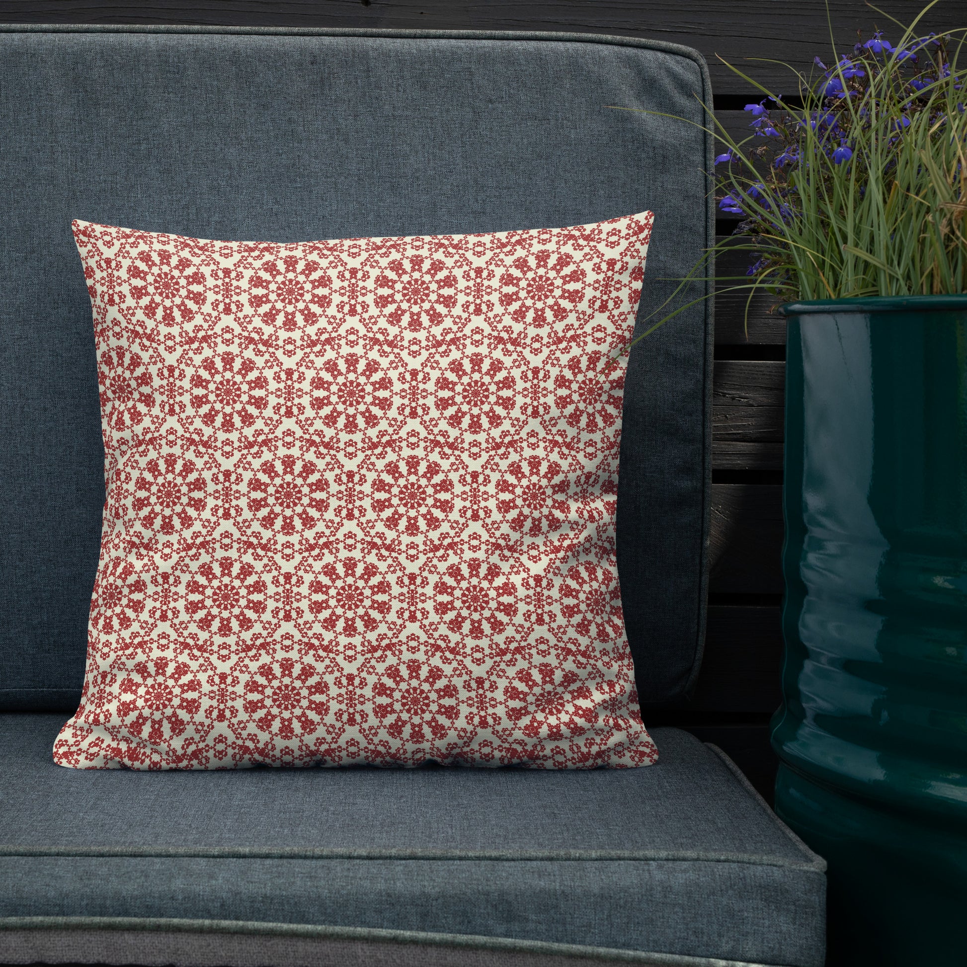 18″×18″ premium throw pillow with the ‘Decagon’ terracotta and beige geometric pattern on a dark teal sofa with blue flowers.