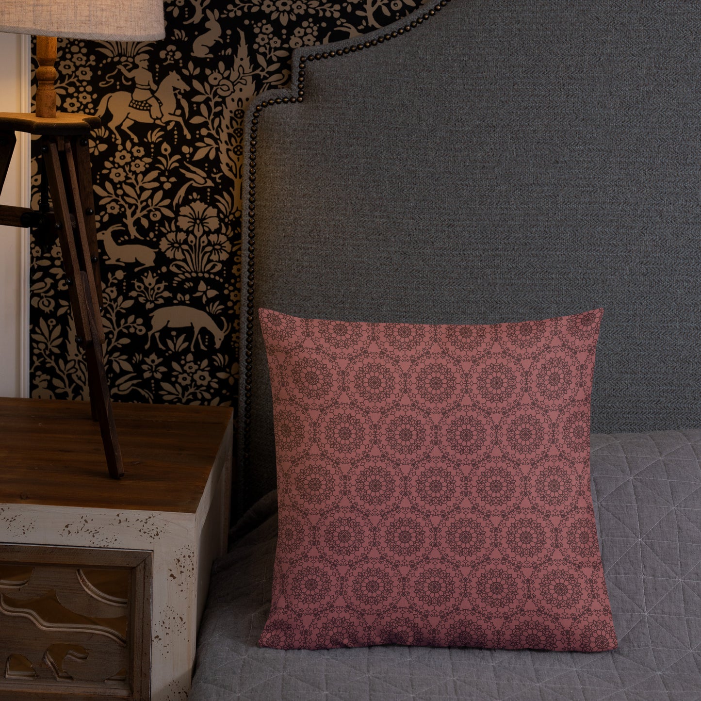 18″×18″ premium throw pillow with the 'Dodecagon' rose geometric pattern on bed beside grey upholstered headboard with lamp.