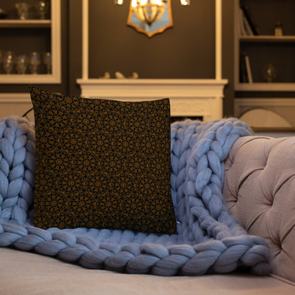 18″×18″ premium throw pillow with the 'Enneagon' black & gold geometric pattern on a sofa with chunky knit blanket.