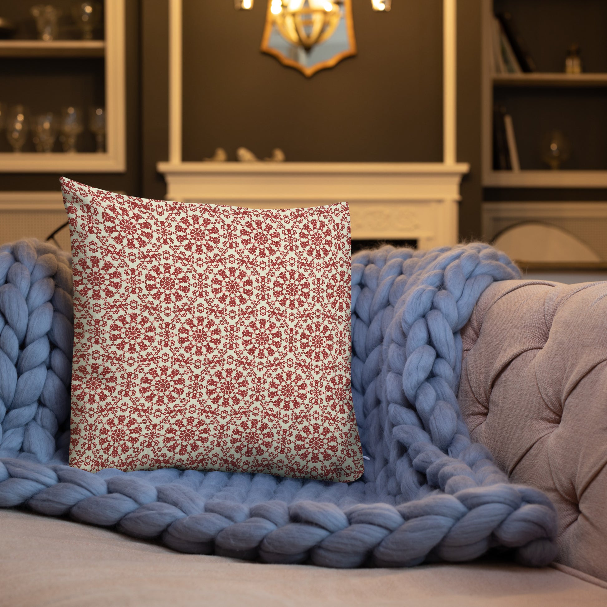 18″×18″ premium throw pillow with the ‘Decagon’ terracotta and beige geometric pattern on a blue sofa with a chunky knit blanket.
