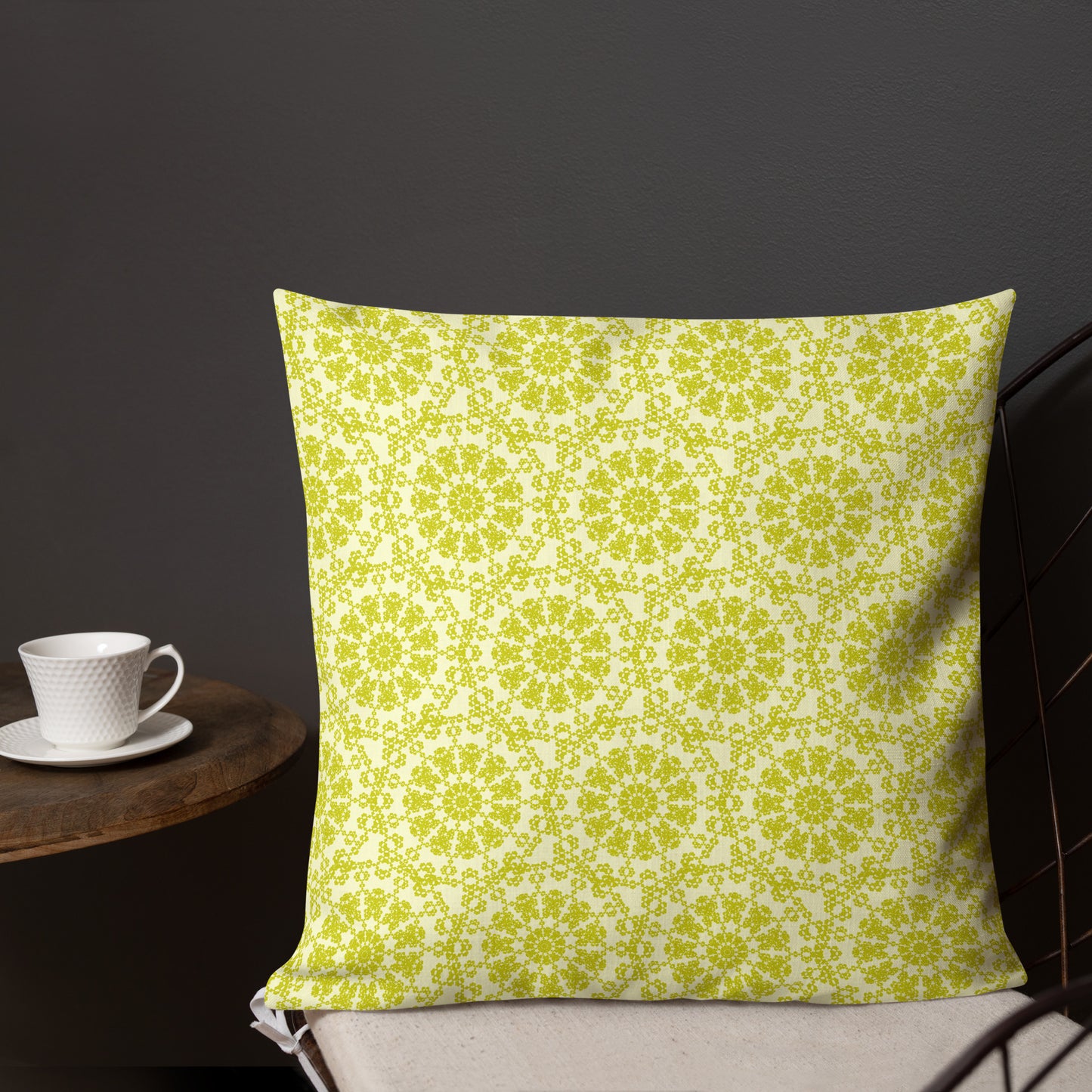 18″×18″ premium throw pillow with the 'Hendecagon' yellow-green geometric pattern on a wire chair with a side table