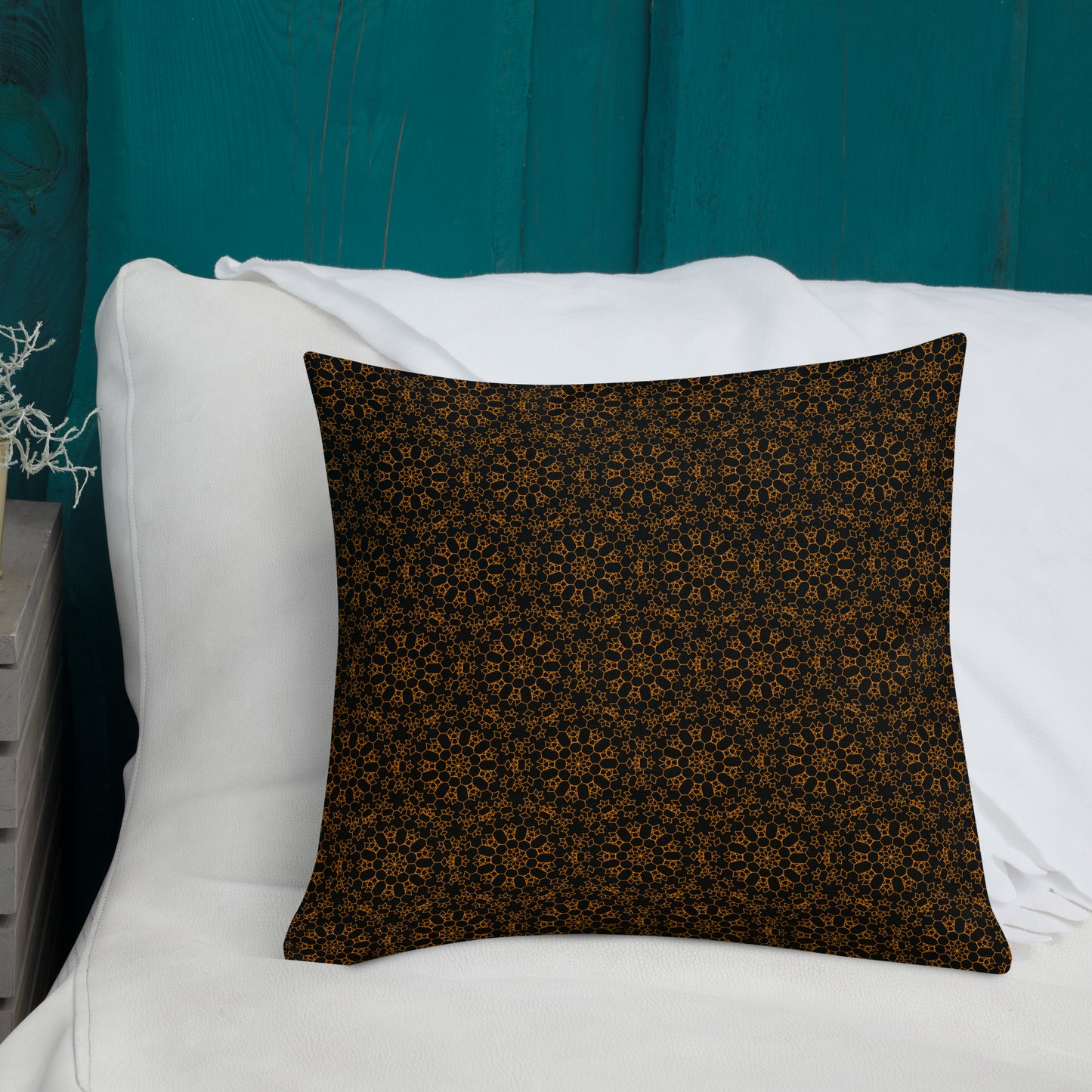 18″×18″ premium throw pillow with the 'Enneagon' black & gold geometric pattern on a bed with white bedding and teal wall.