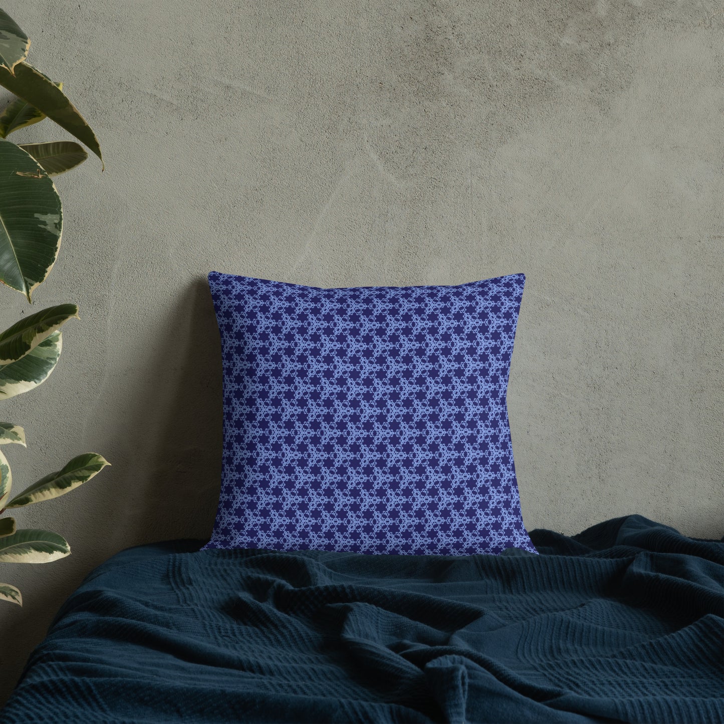18″×18″ premium throw pillow with the 'Trigon' navy and blue geometric pattern on a bed.