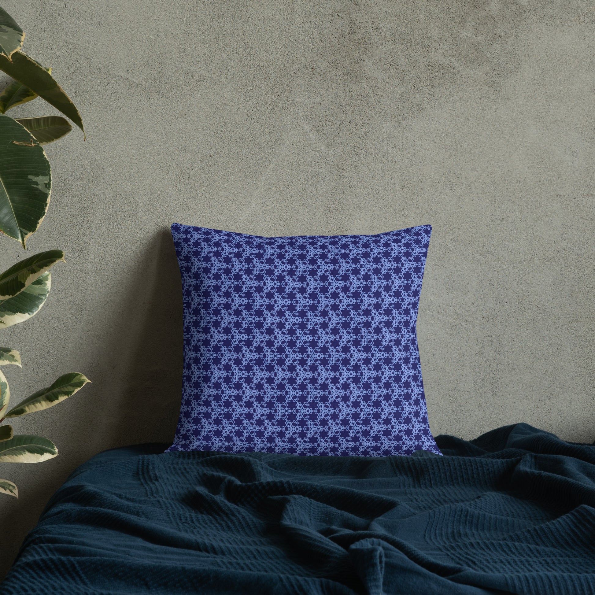 18″×18″ premium throw pillow with the 'Trigon' navy and blue geometric pattern on a bed.