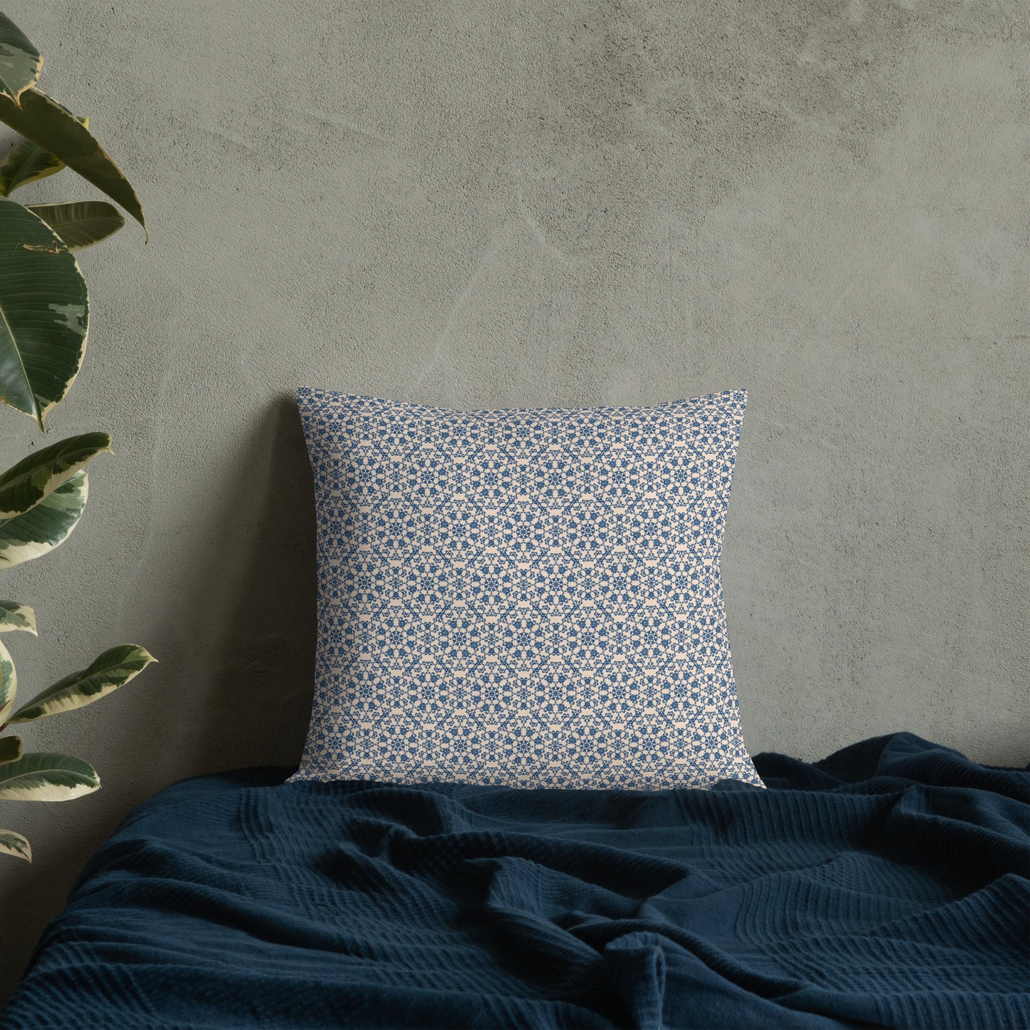 18″×18″ premium throw pillow with the ‘Octagon’ navy and beige geometric pattern on a bed with dark blanket.