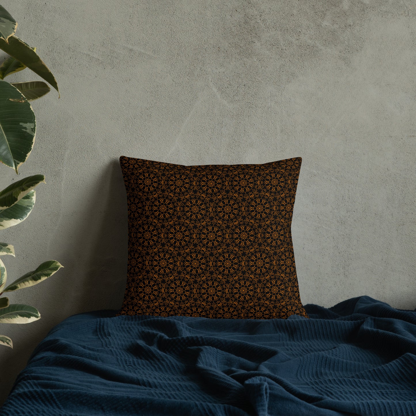 18″×18″ premium throw pillow with the 'Enneagon' black & gold geometric pattern on a bed with dark teal blanket.