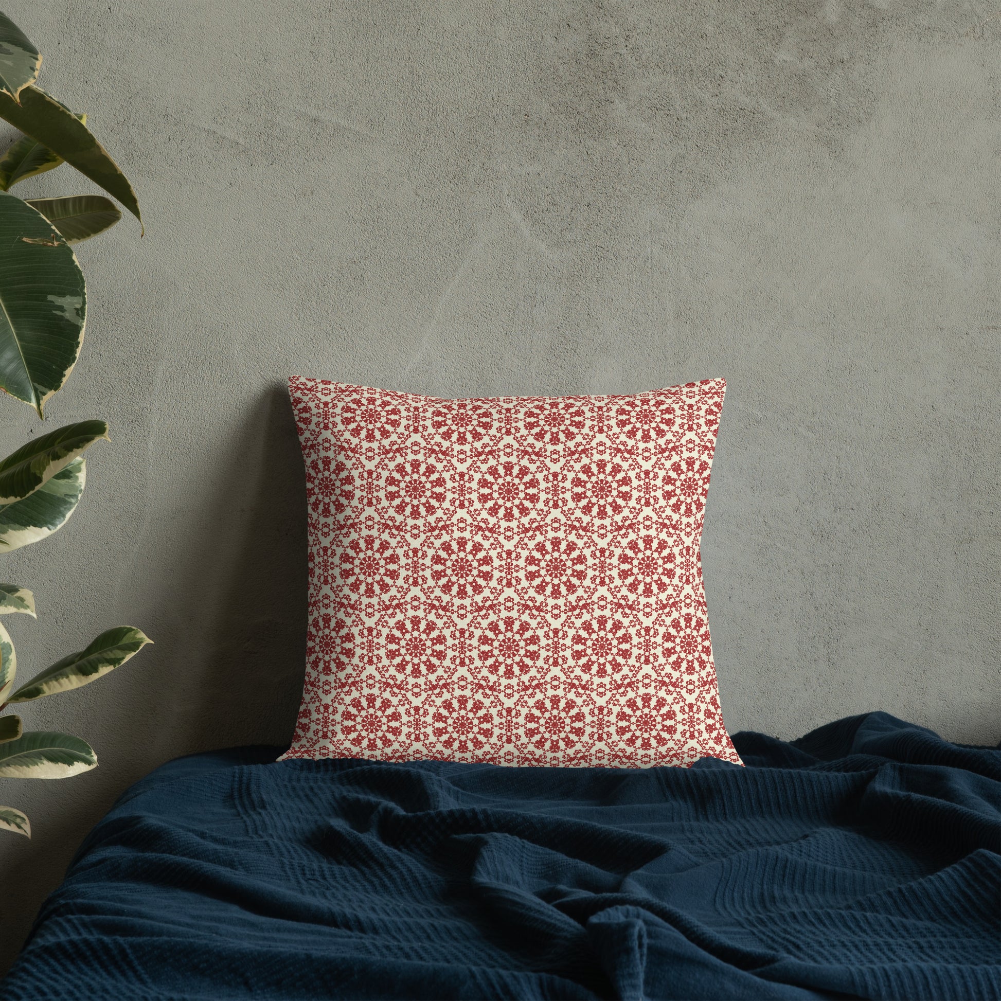18″×18″ premium throw pillow with the ‘Decagon’ terracotta and beige geometric pattern on a bed with a dark navy blanket.