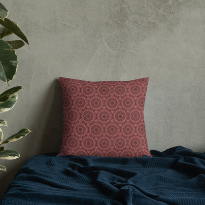 18″×18″ premium throw pillow with the 'Dodecagon' rose geometric pattern on bed with dark teal blanket against concrete wall.