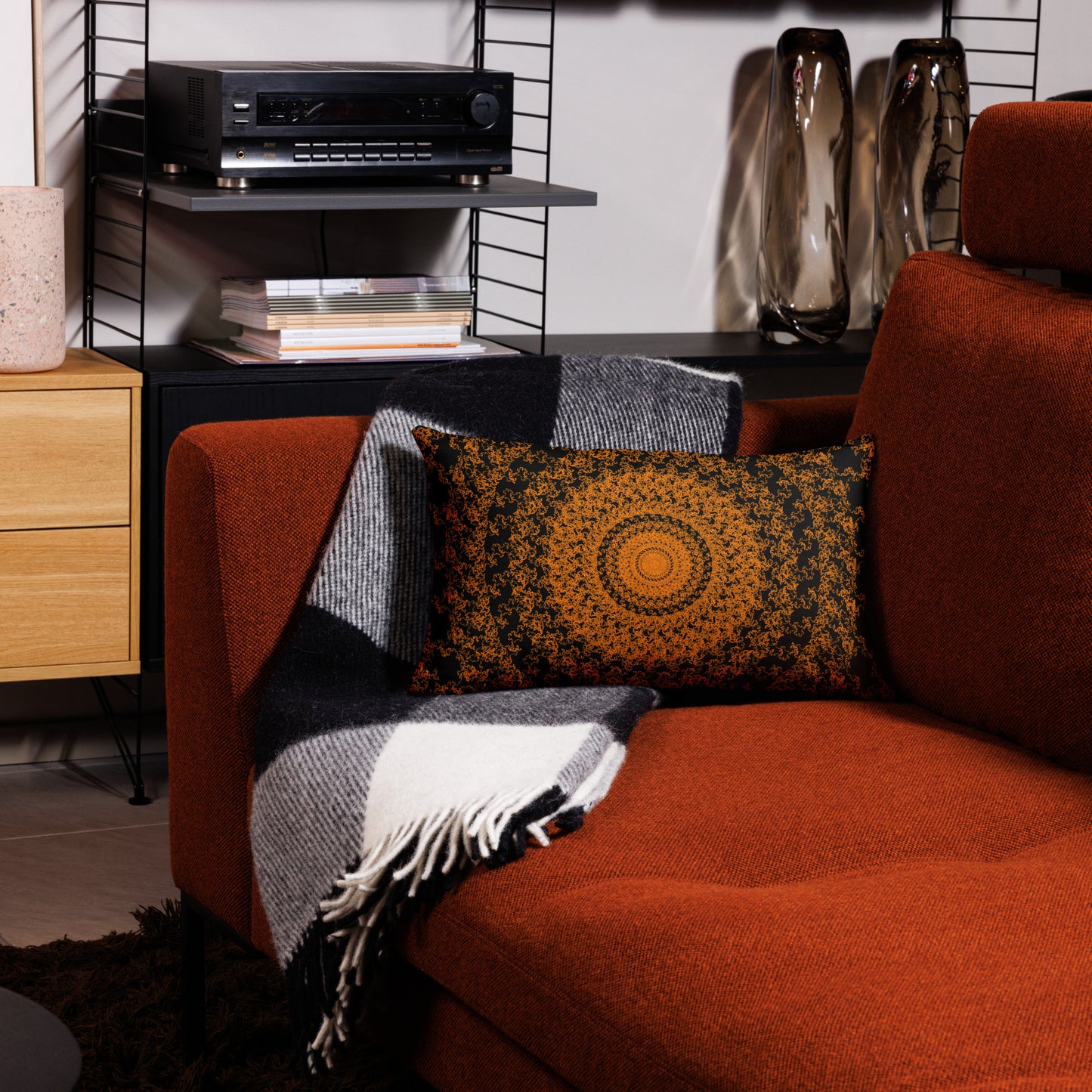 20″×12″ premium throw pillow with the 'The Sun' orange and black geometric design on a couch.