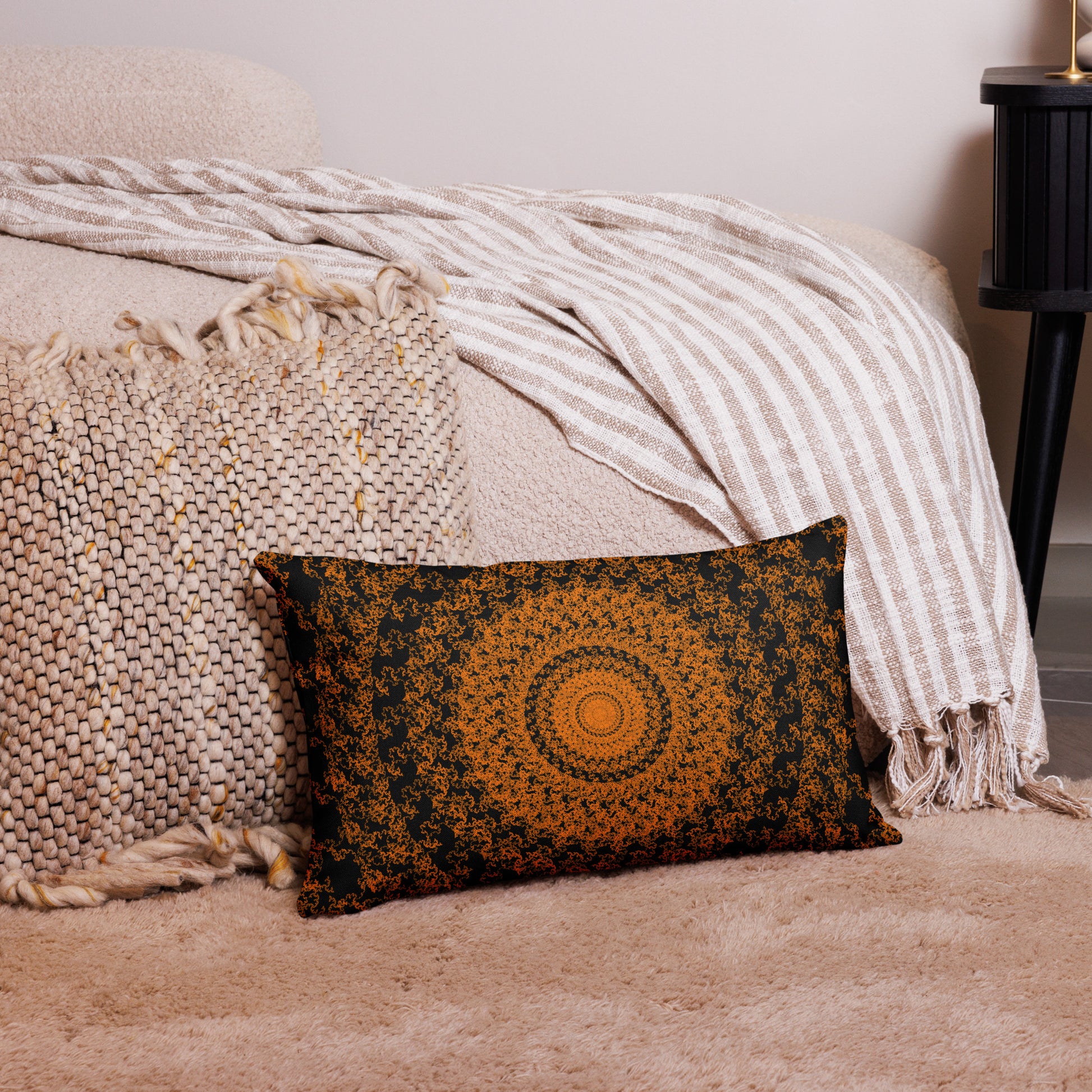 20″×12″ premium throw pillow with the 'The Sun' orange and black geometric design on a couch.