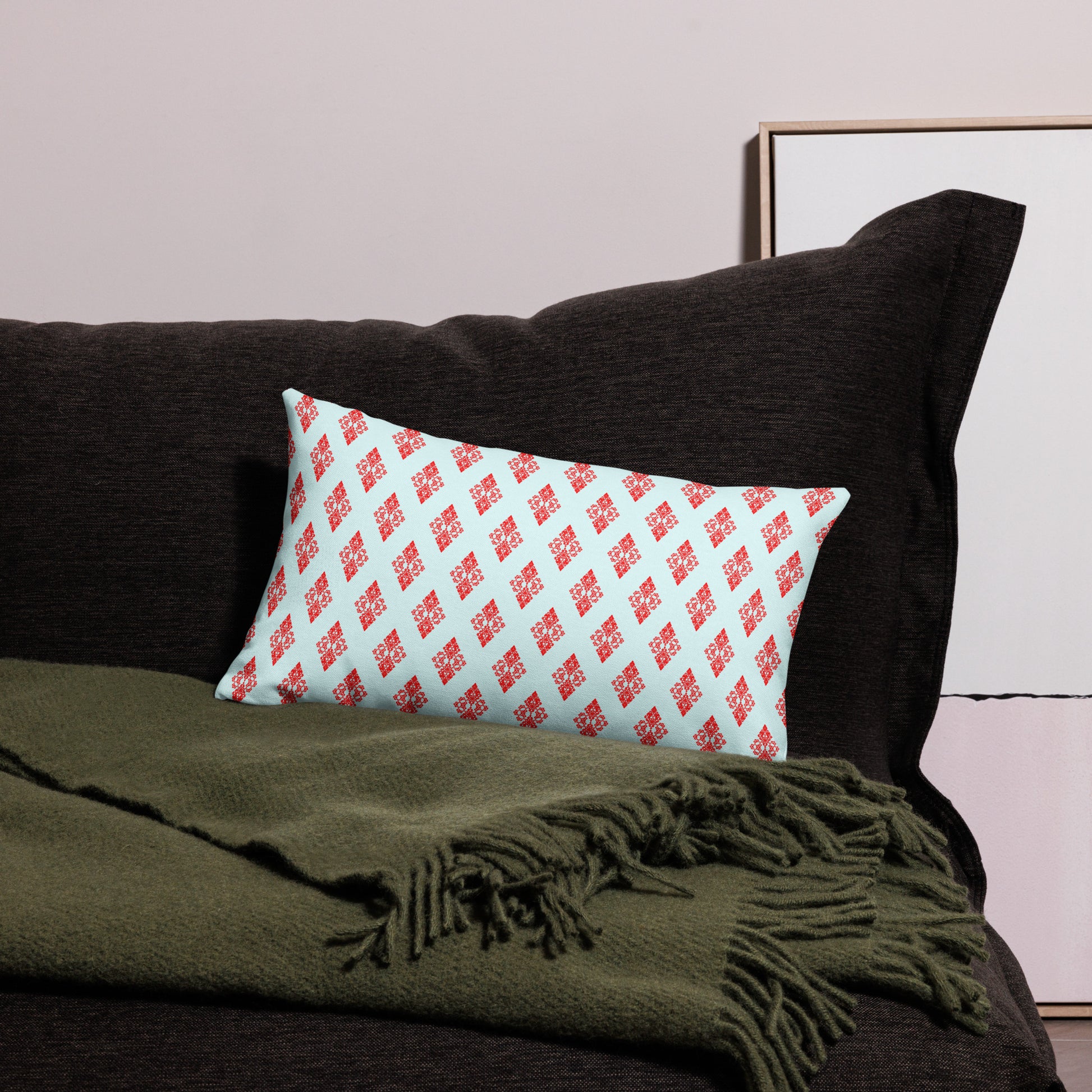 20″×12″ premium throw pillow with the 'Digon' sky blue and red geometric pattern on a couch.