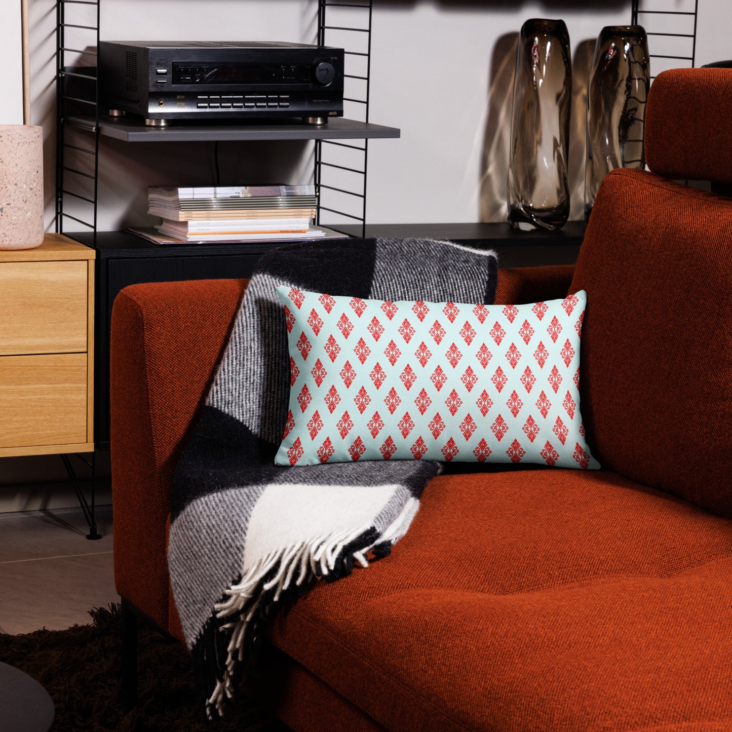 20″×12″ premium throw pillow with the 'Digon' sky blue and red geometric pattern on a couch.