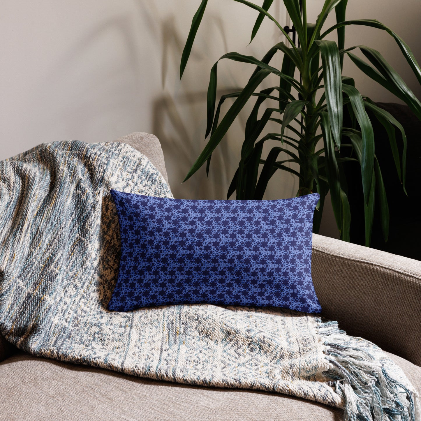 20″×12″ premium throw pillow with the 'Trigon' navy and blue geometric pattern on a couch.