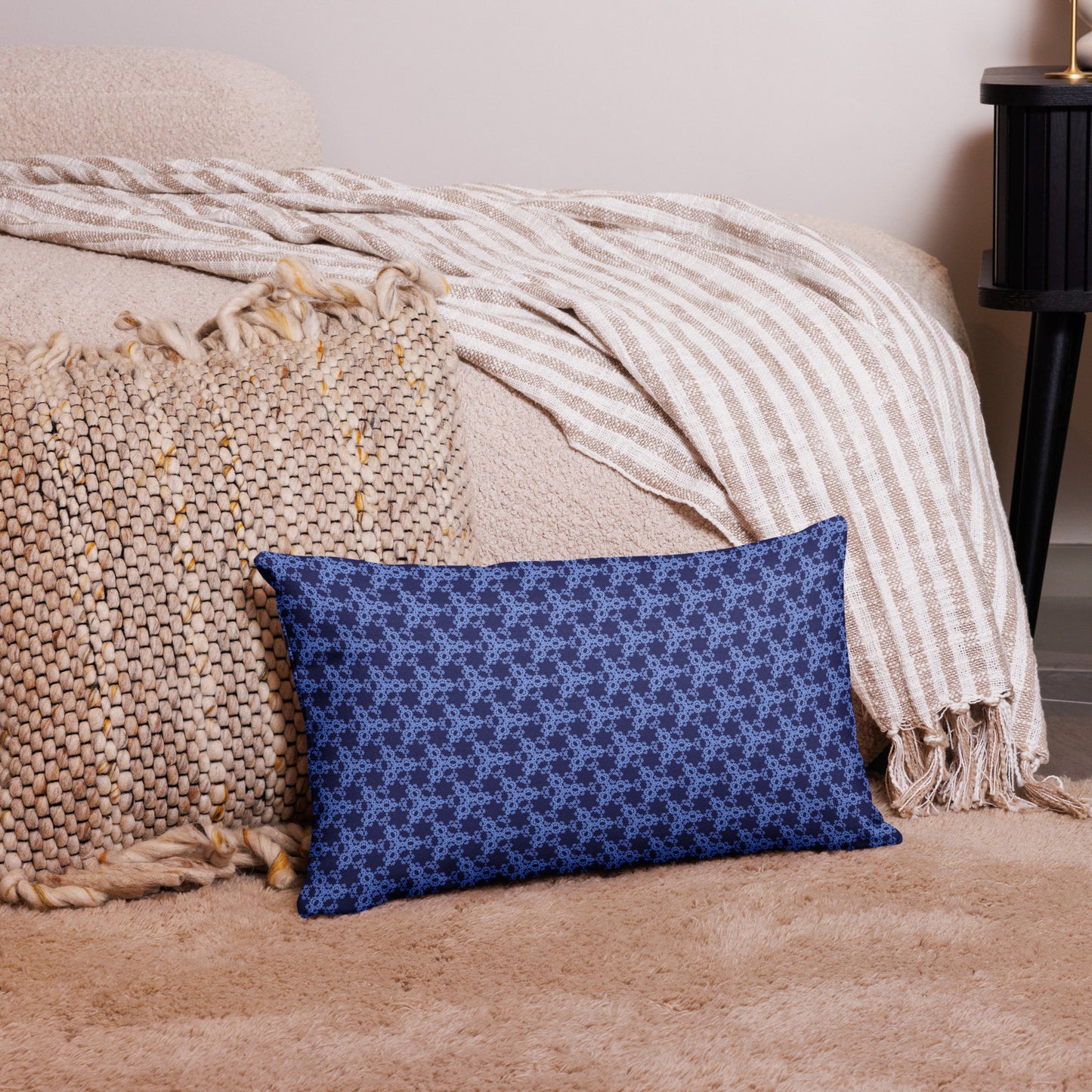 20″×12″ premium throw pillow with the 'Trigon' navy and blue geometric pattern on a couch.
