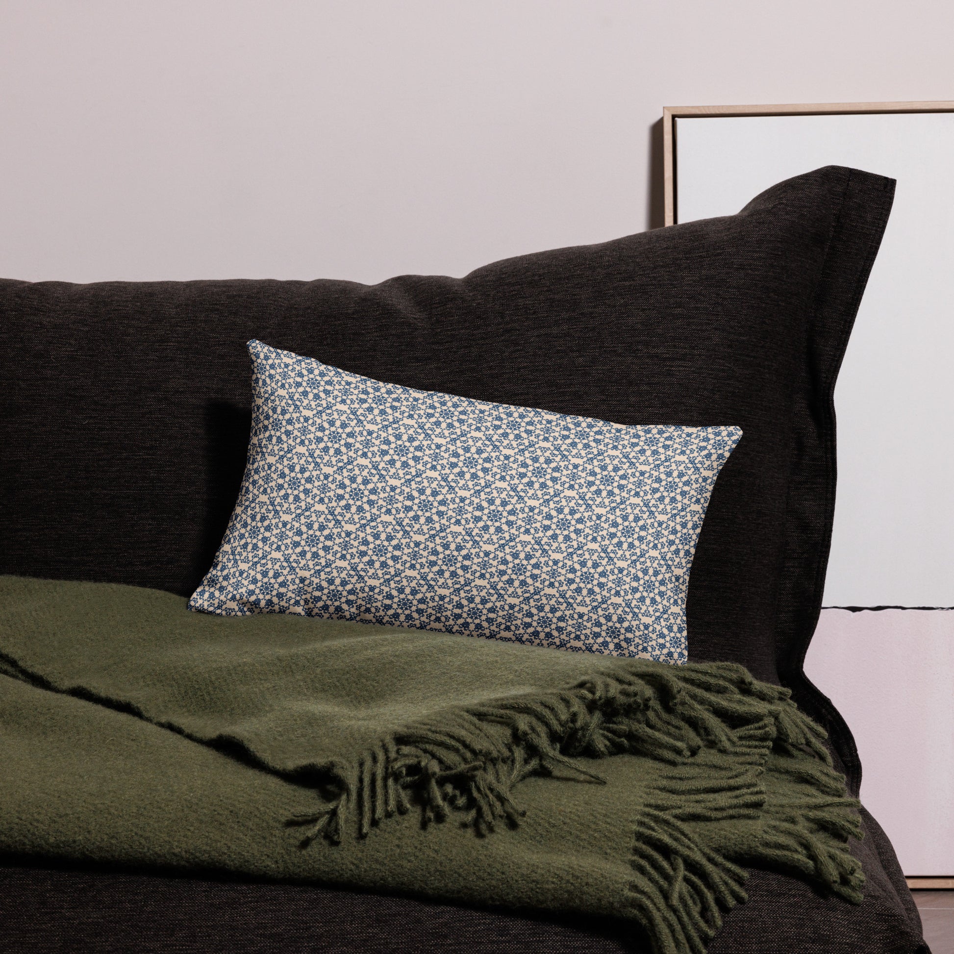 20″×12″ premium throw pillow with the ‘Octagon’ navy and beige geometric pattern on a dark sofa with throw blanket.