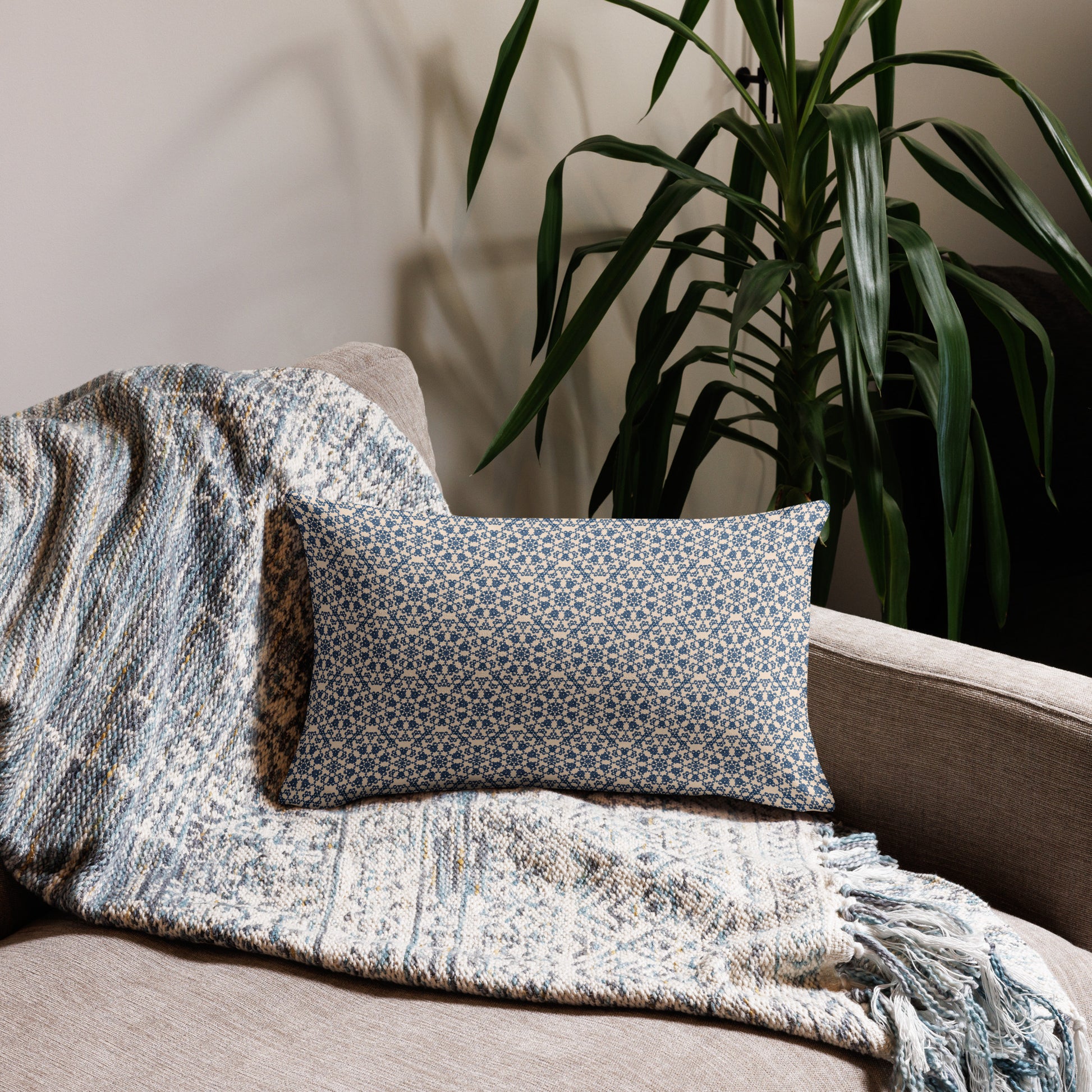 20″×12″ premium throw pillow with the ‘Octagon’ navy and beige geometric pattern on a sofa with fringed blanket.