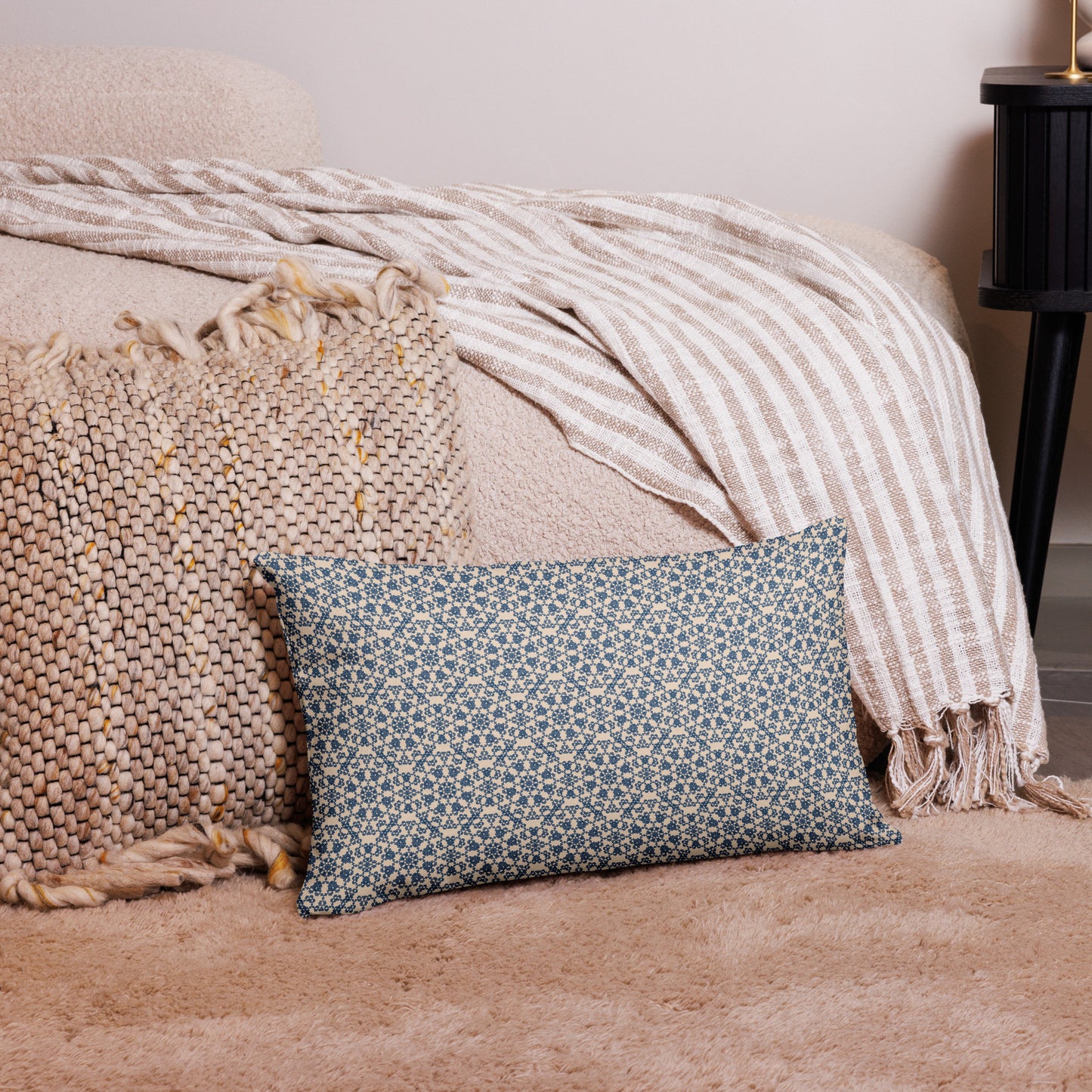 20″×12″ premium throw pillow with the ‘Octagon’ navy and beige geometric pattern on a bed with striped blanket.