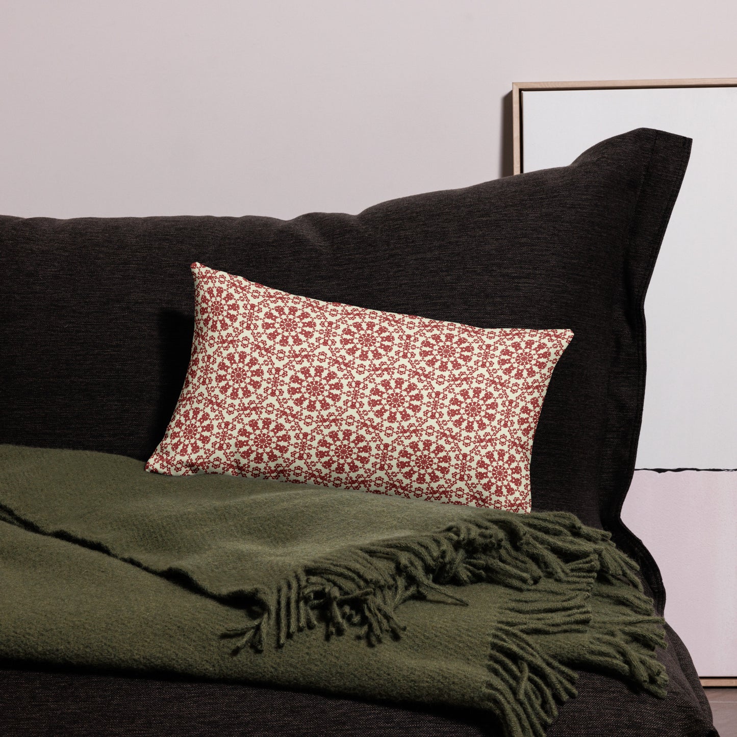 20″×12″ premium throw pillow with the ‘Decagon’ terracotta and beige geometric pattern on a black sofa with an olive throw.