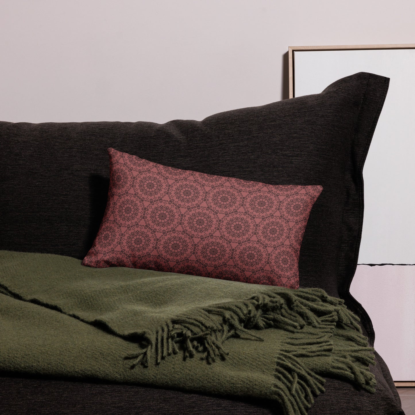20″×12″ premium throw pillow with the 'Dodecagon' rose geometric pattern on dark sofa with green fringed throw.