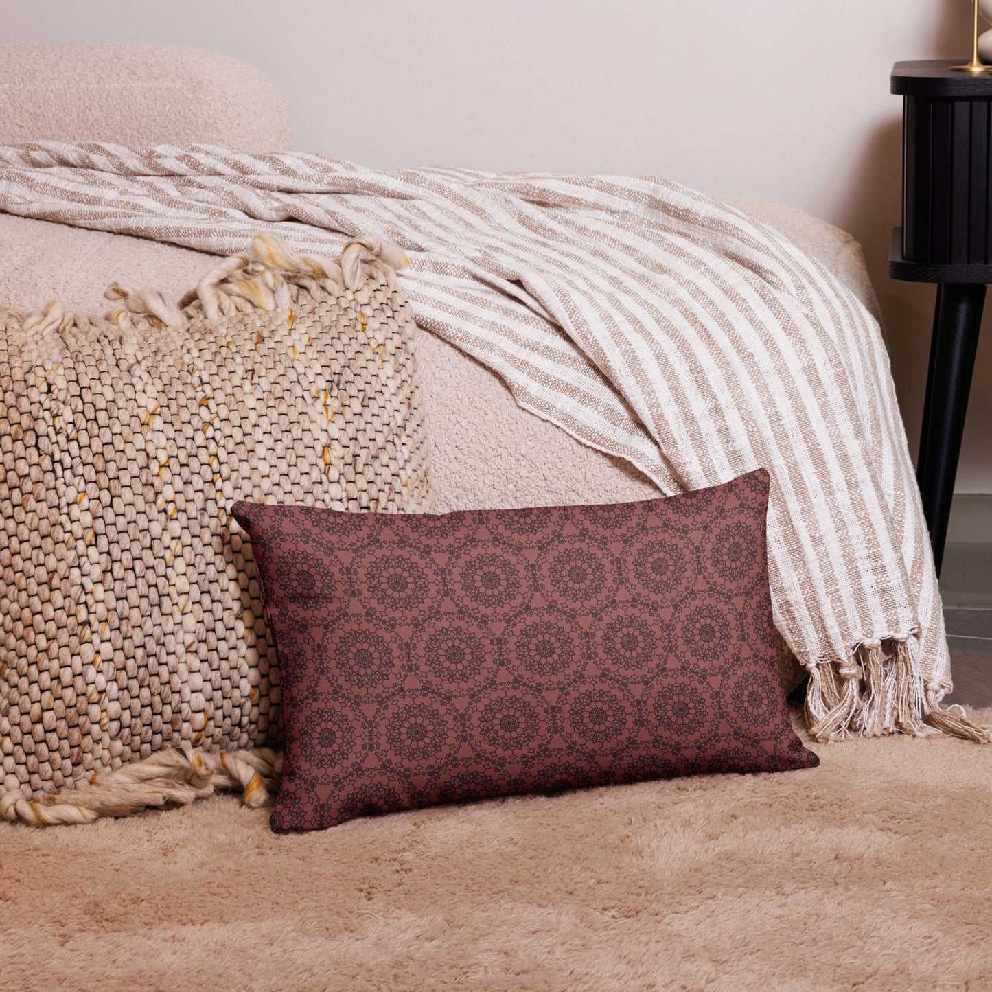 20″×12″ premium throw pillow with the 'Dodecagon' rose geometric pattern on carpet beside bed with striped throw.