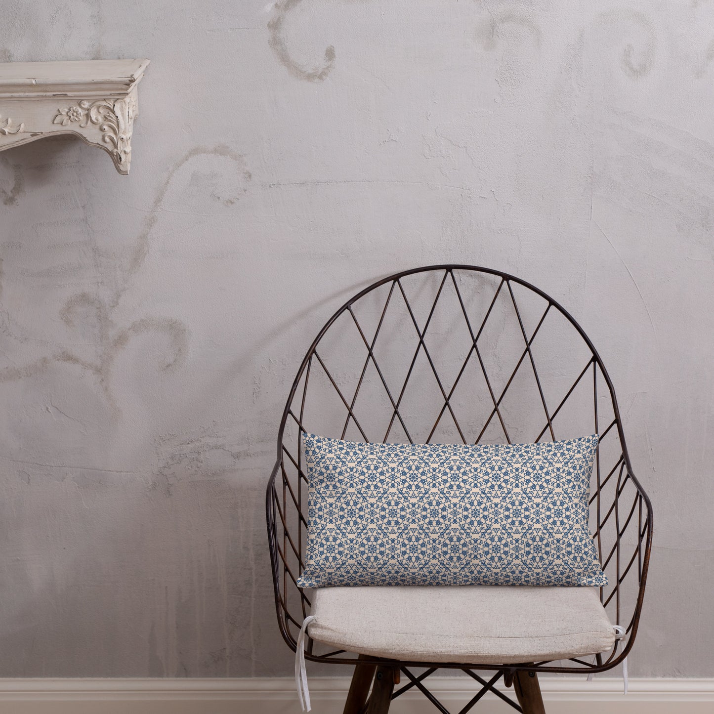 20″×12″ premium throw pillow with the ‘Octagon’ navy and beige geometric pattern on a wire chair.