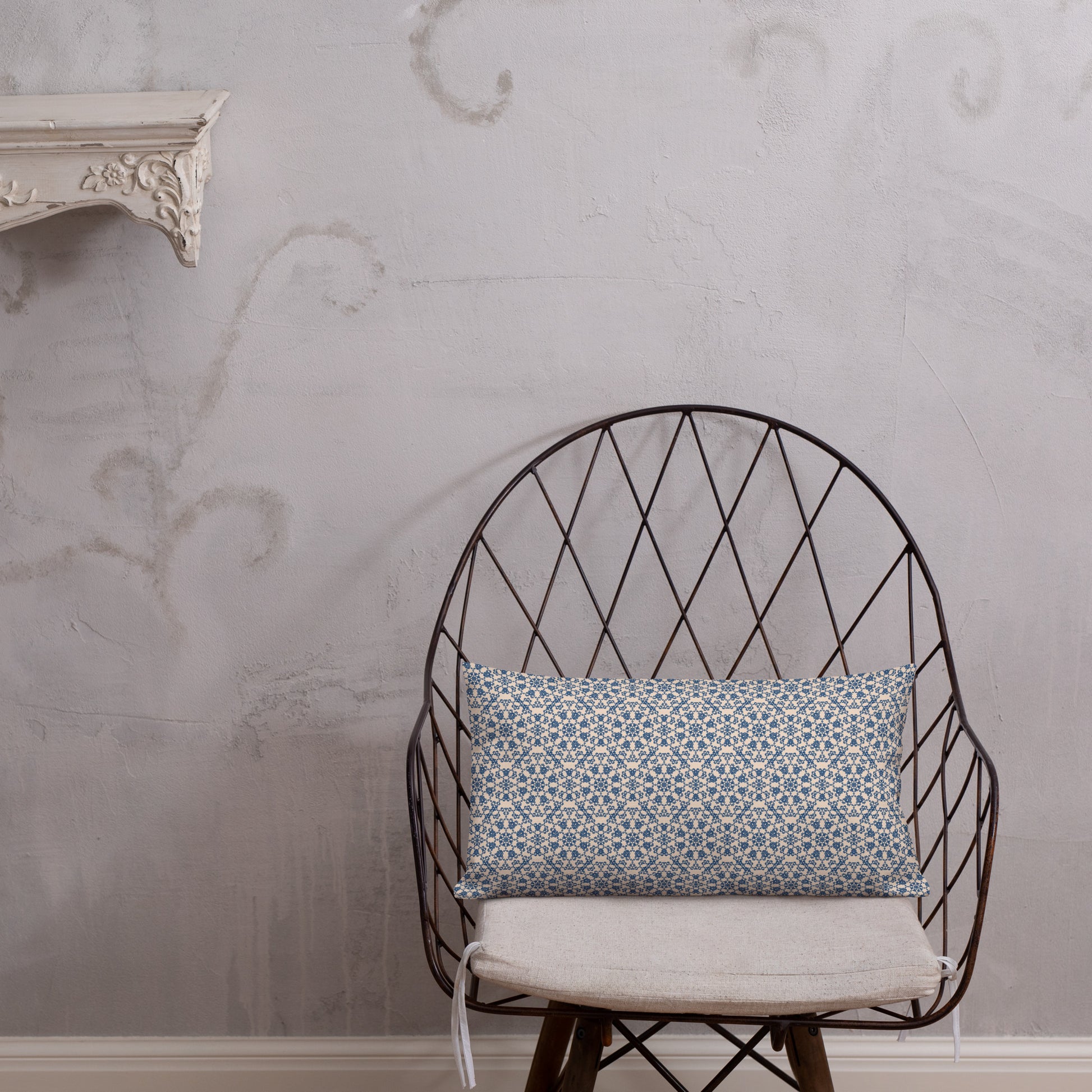 20″×12″ premium throw pillow with the ‘Octagon’ navy and beige geometric pattern on a wire chair.