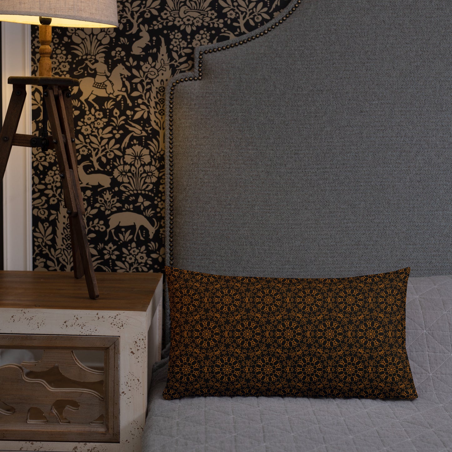20″×12″ premium throw pillow with the 'Enneagon' black & gold geometric pattern on a bed with upholstered headboard.