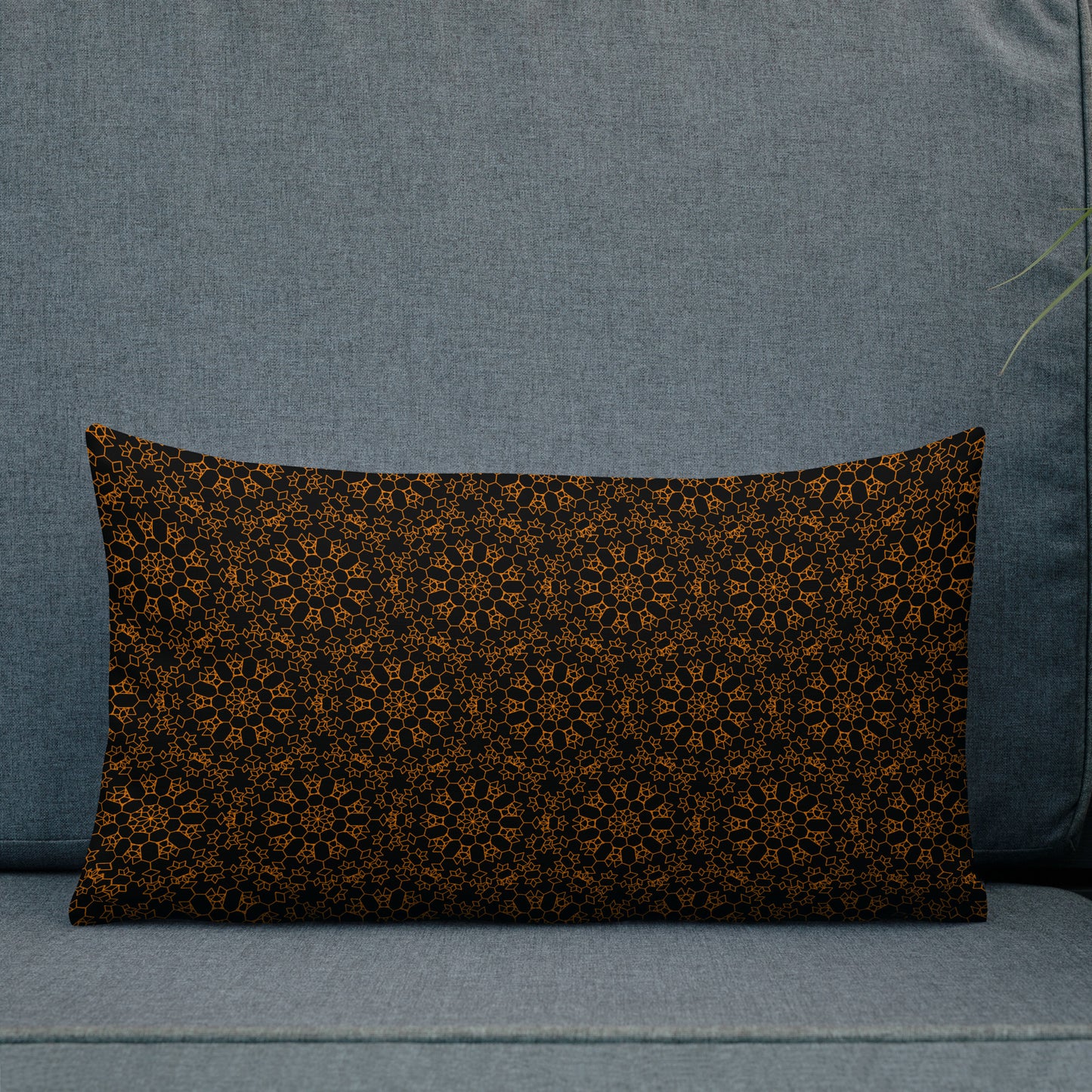 20″×12″ premium throw pillow with the 'Enneagon' black & gold geometric pattern on an outdoor sofa with dark slat wall.