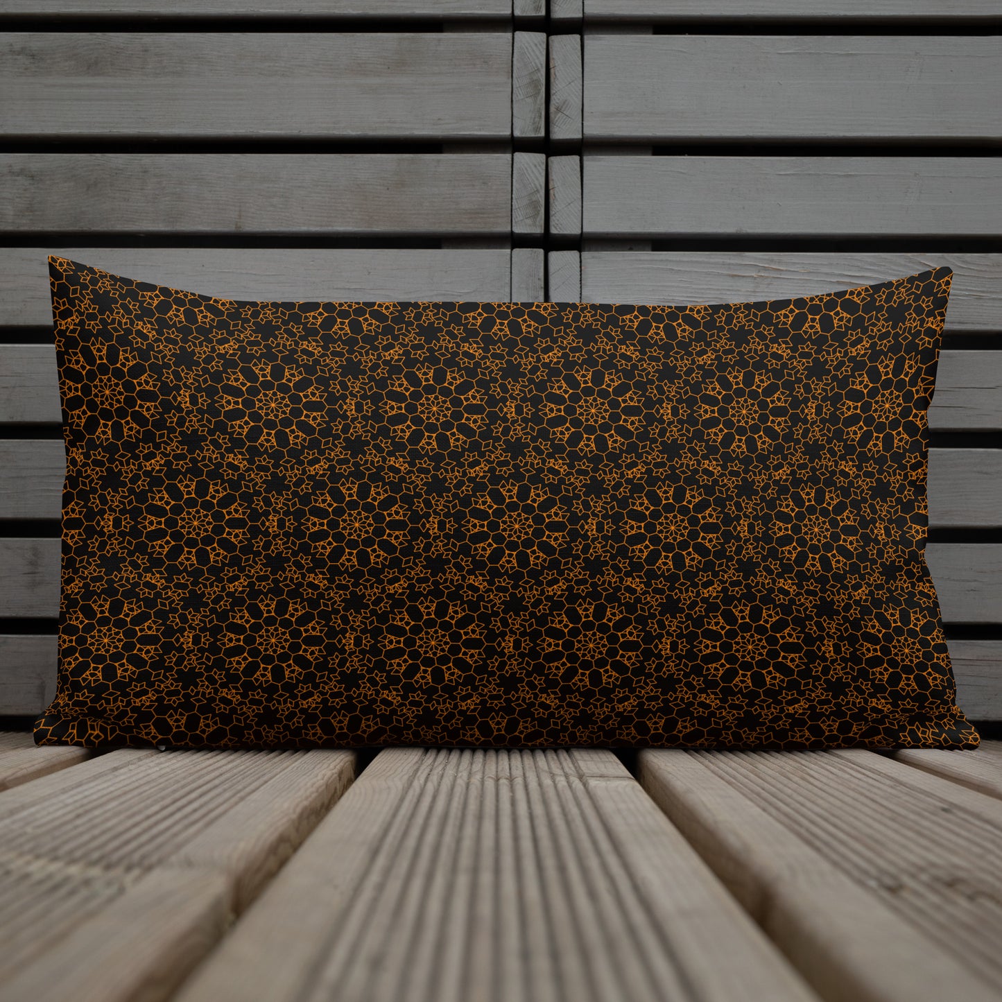 20″×12″ premium throw pillow with the 'Enneagon' black & gold geometric pattern on a chair with coffee cup on side table.