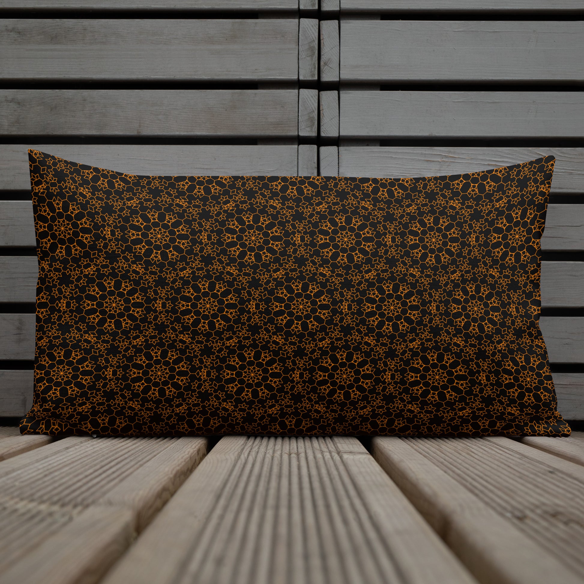 20″×12″ premium throw pillow with the 'Enneagon' black & gold geometric pattern on a chair with coffee cup on side table.