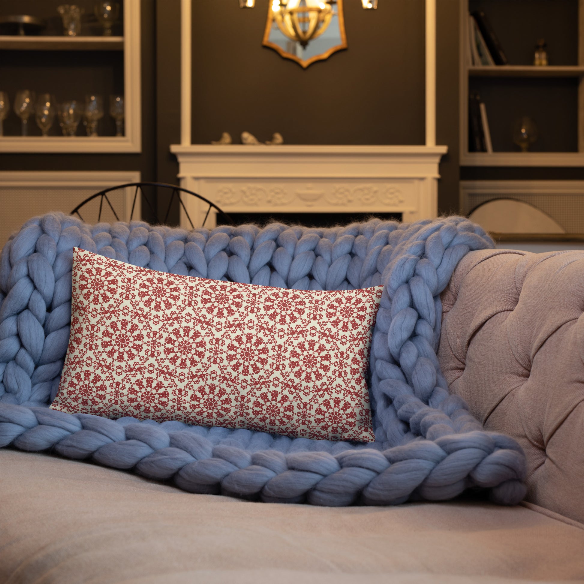 20″×12″ premium throw pillow with the ‘Decagon’ terracotta and beige geometric pattern on a blue sofa with a chunky knit blanket.
