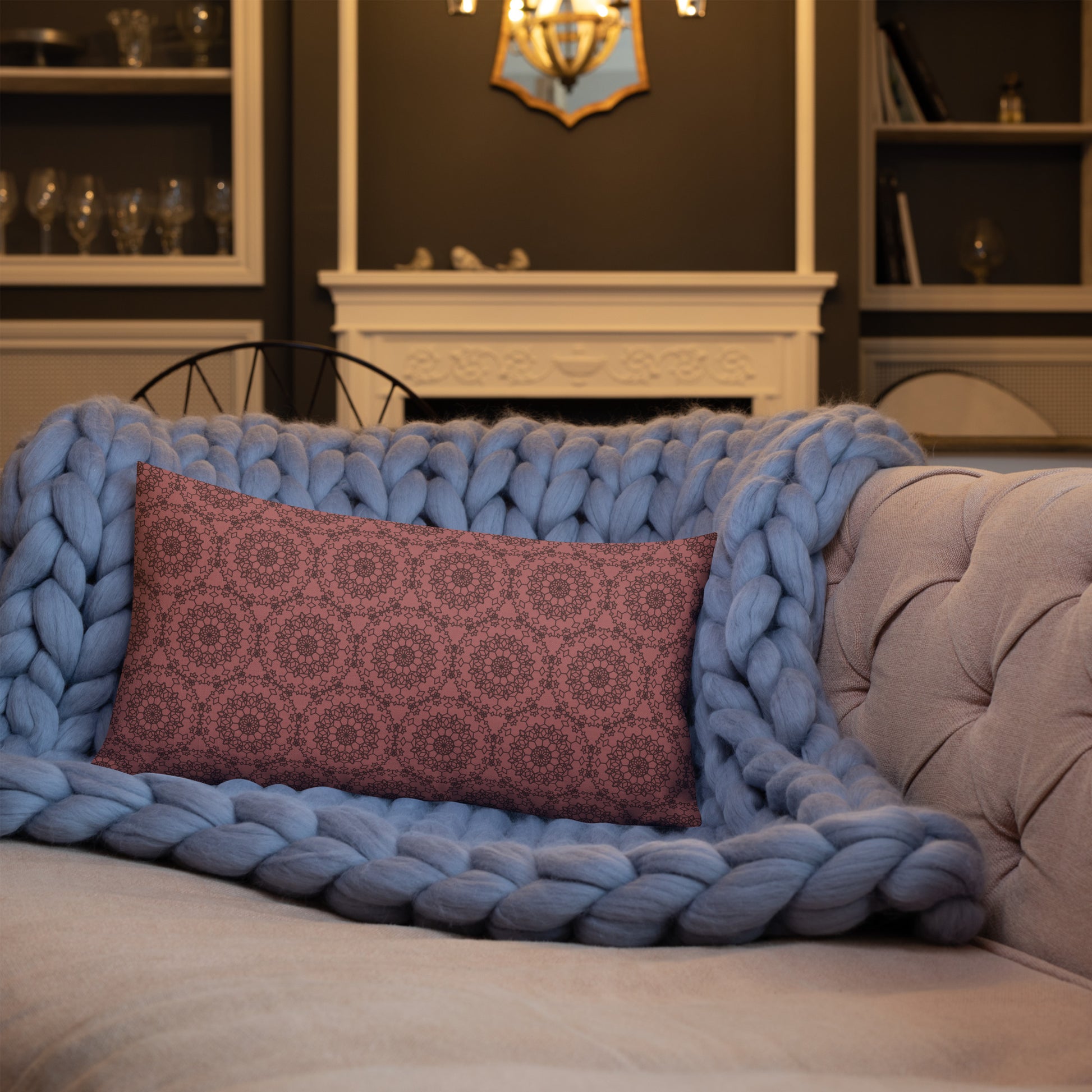 20″×12″ premium throw pillow with the 'Dodecagon' rose geometric pattern on tufted sofa with chunky blue knit blanket.