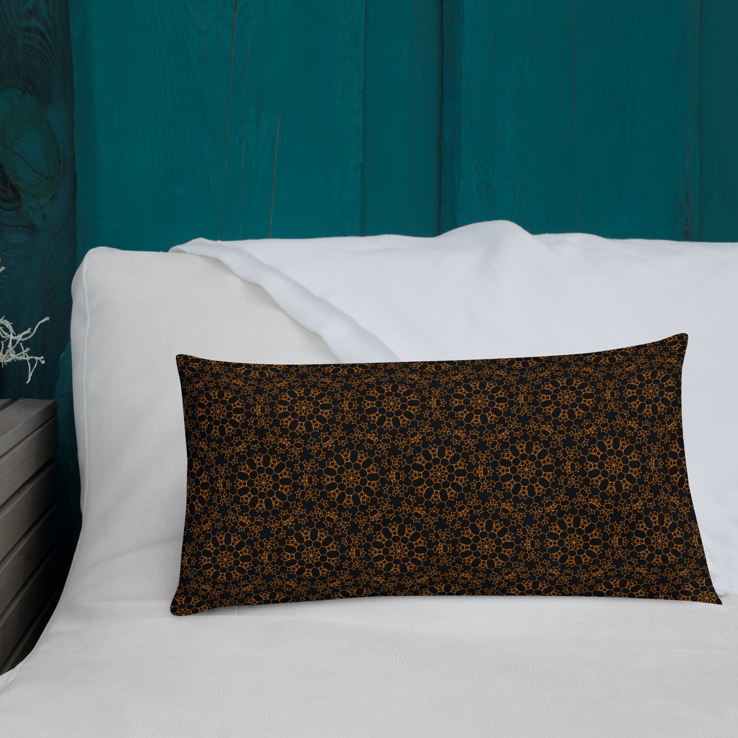 20″×12″ premium throw pillow with the 'Enneagon' black & gold geometric pattern on a bed with white bedding and teal wall.