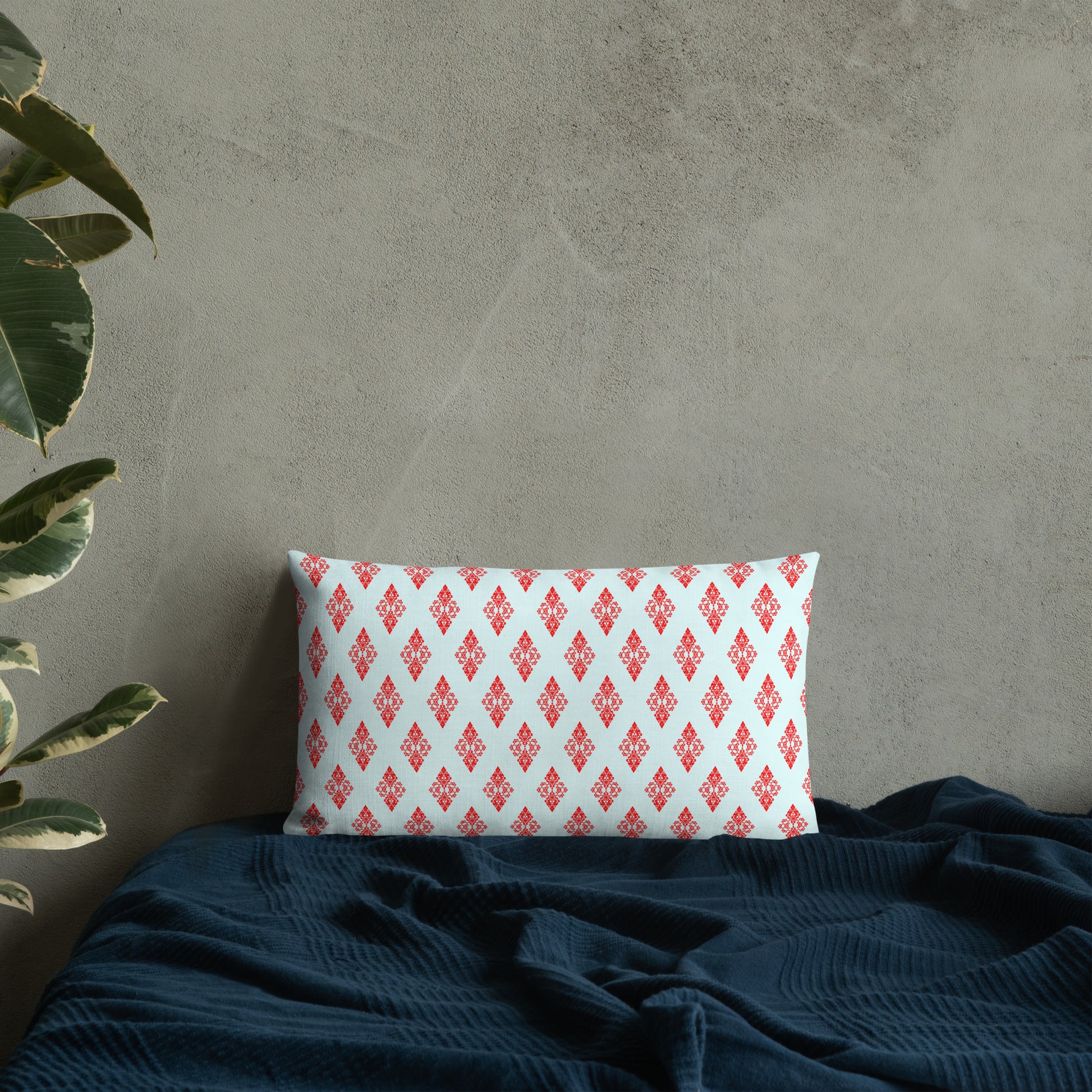 20″×12″ premium throw pillow with the 'Digon' sky blue and red geometric pattern on a bed.