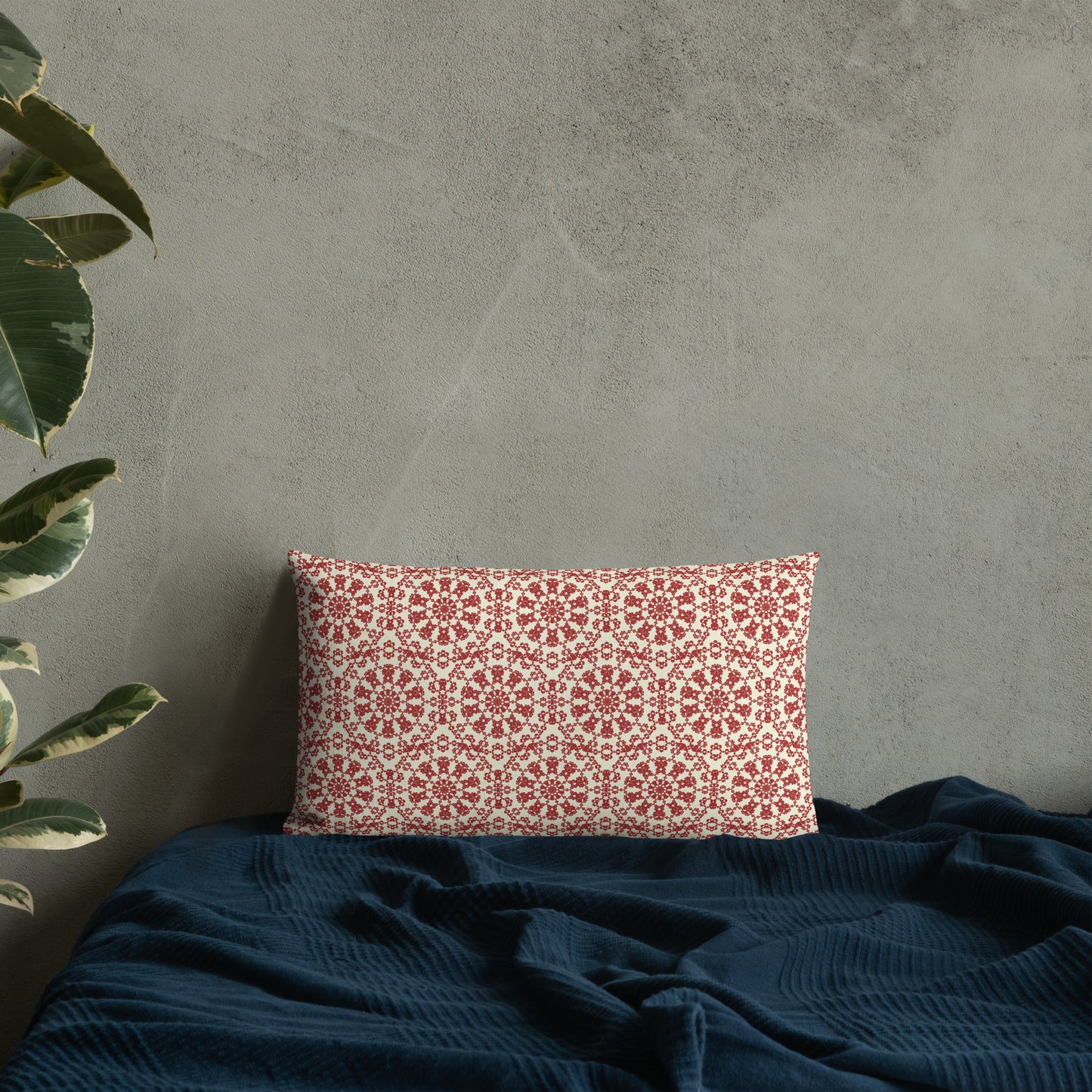 20″×12″ premium throw pillow with the ‘Decagon’ terracotta and beige geometric pattern on a bed with a dark navy blanket.