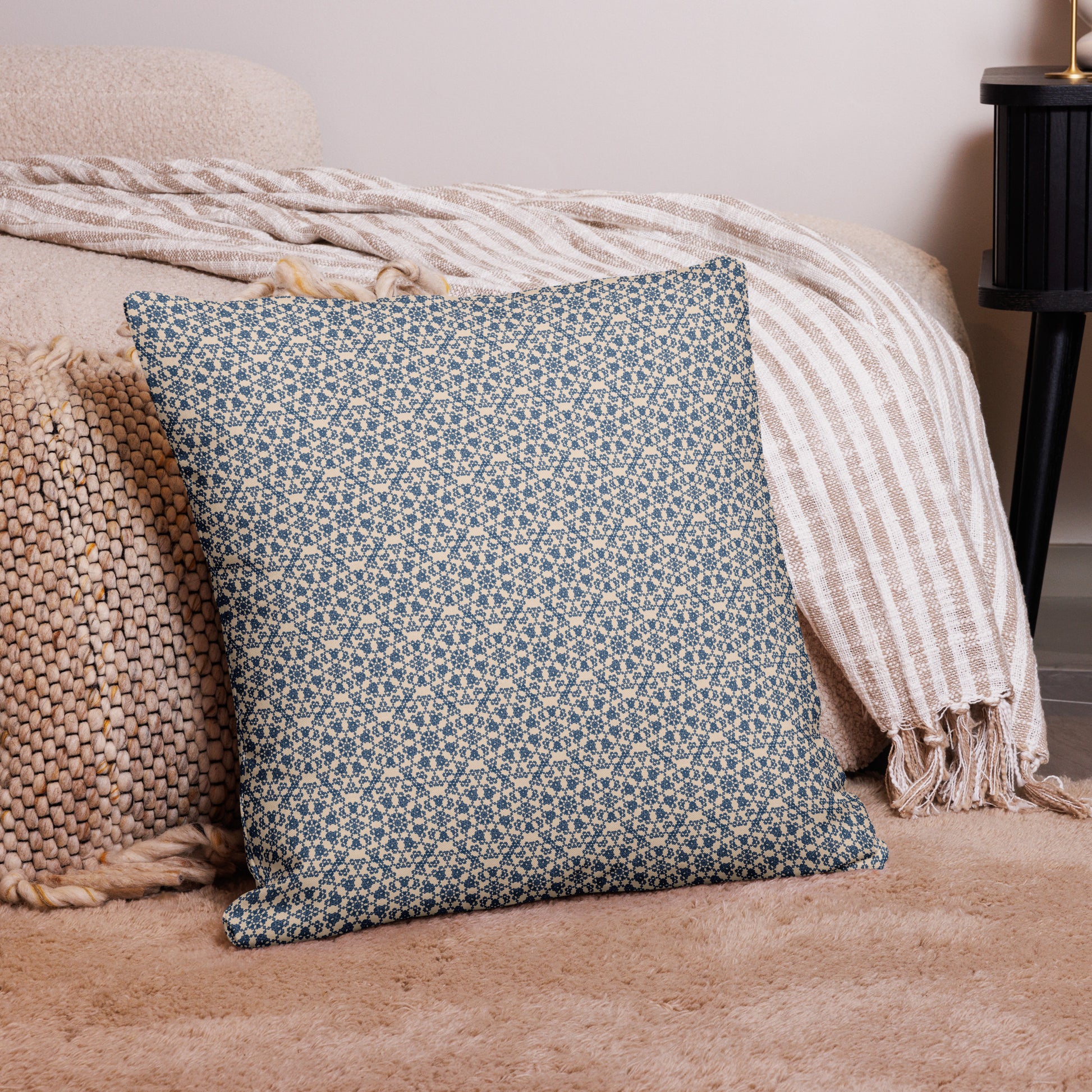 22″×22″ premium throw pillow with the ‘Octagon’ navy and beige geometric pattern on a bed with striped blanket.