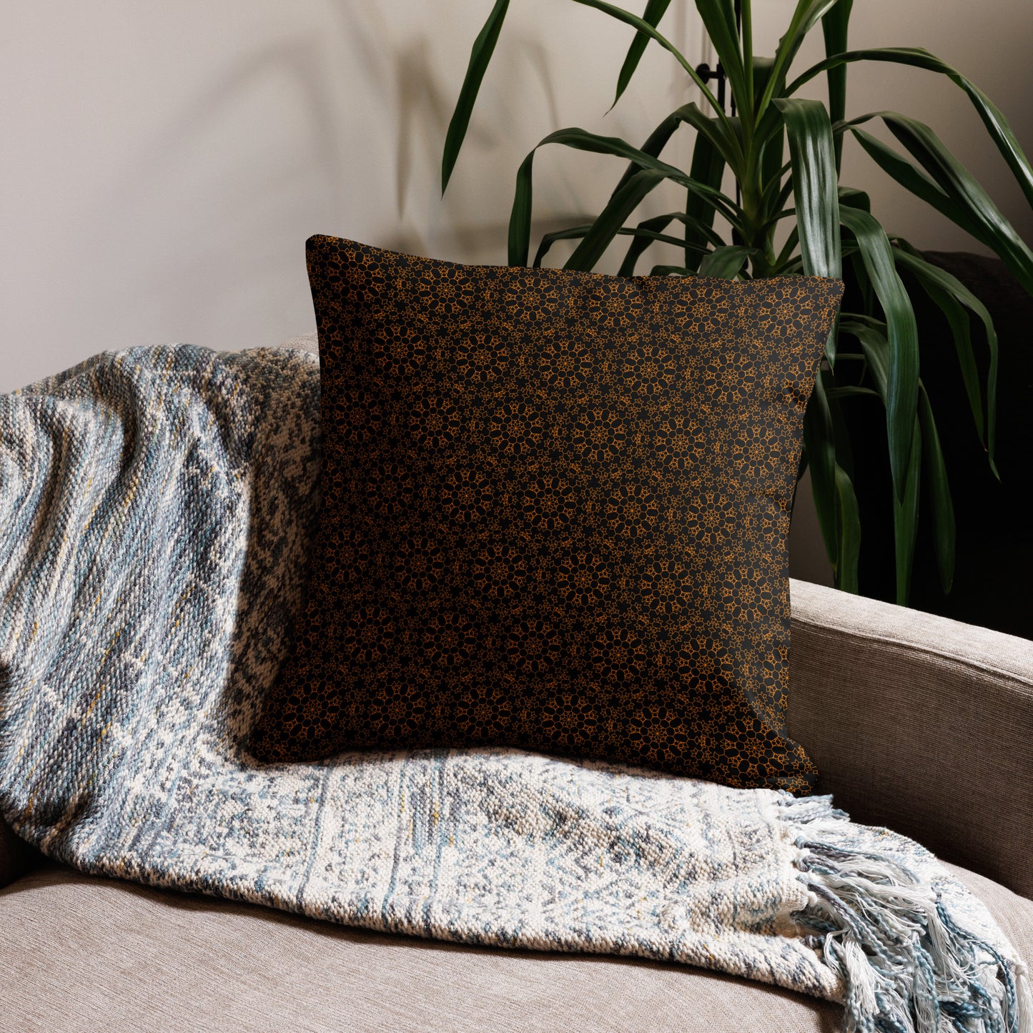 22″×22″ premium throw pillow with the 'Enneagon' black & gold geometric pattern on a sofa with textured throw blanket.