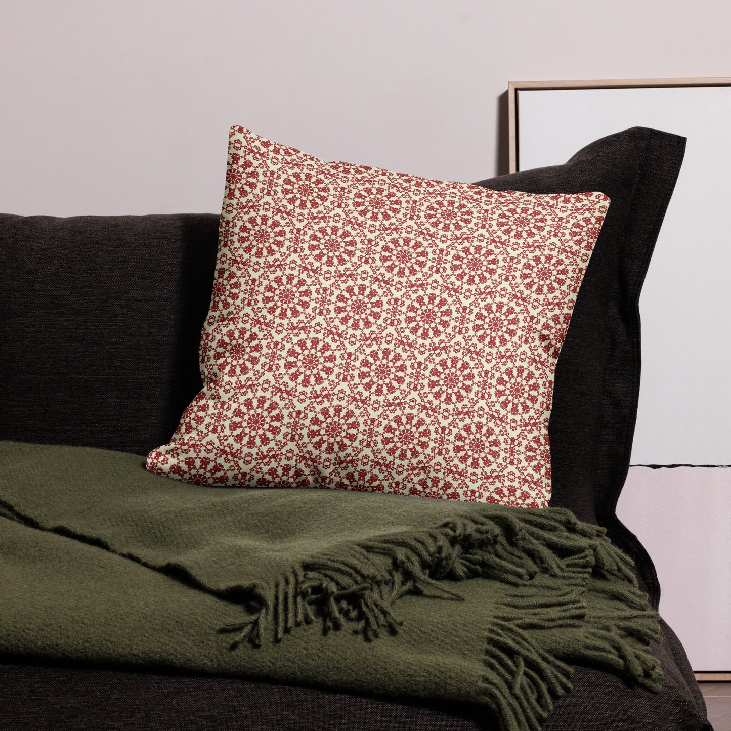 22″×22″ premium throw pillow with the ‘Decagon’ terracotta and beige geometric pattern on a black sofa with an olive throw.