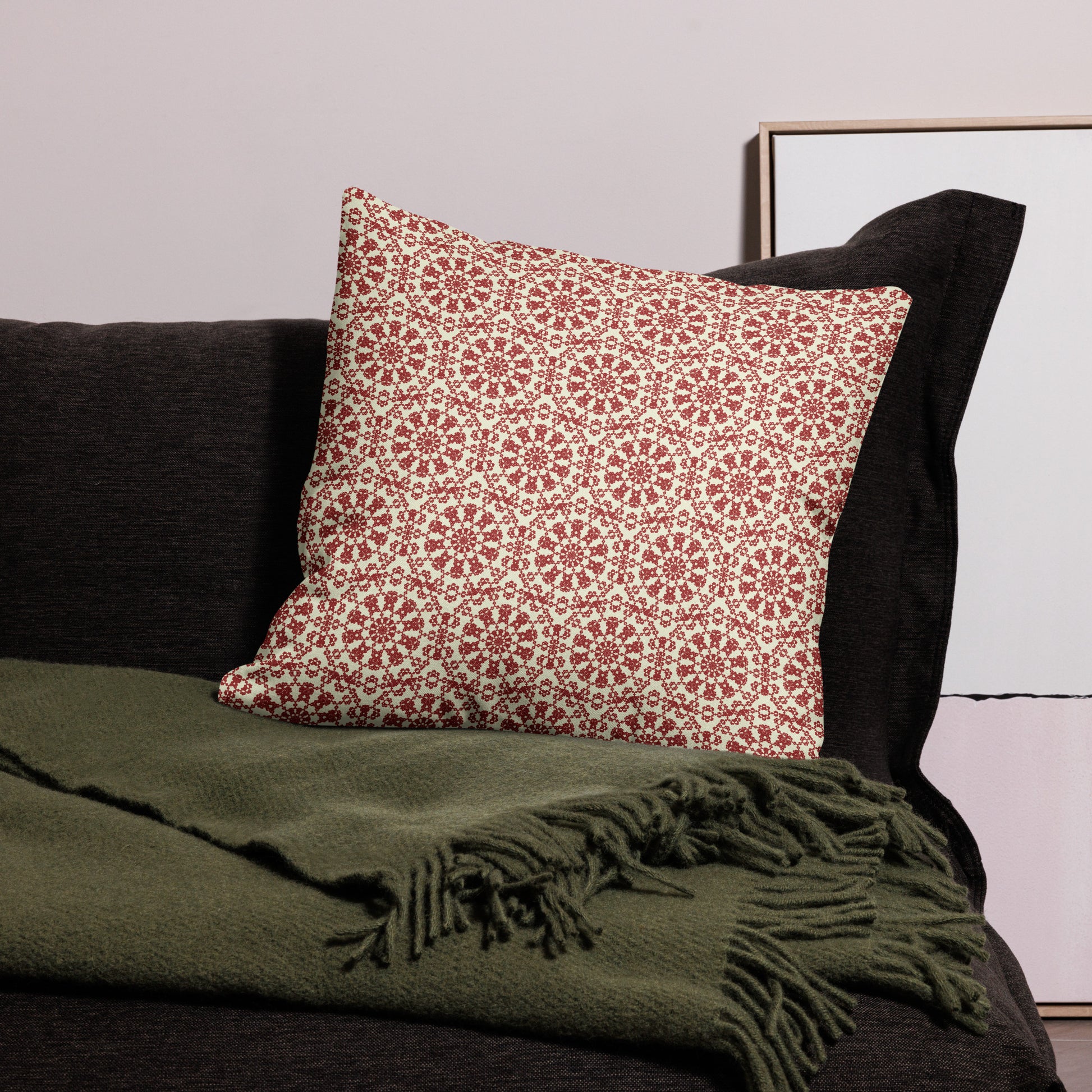 22″×22″ premium throw pillow with the ‘Decagon’ terracotta and beige geometric pattern on a black sofa with an olive throw.