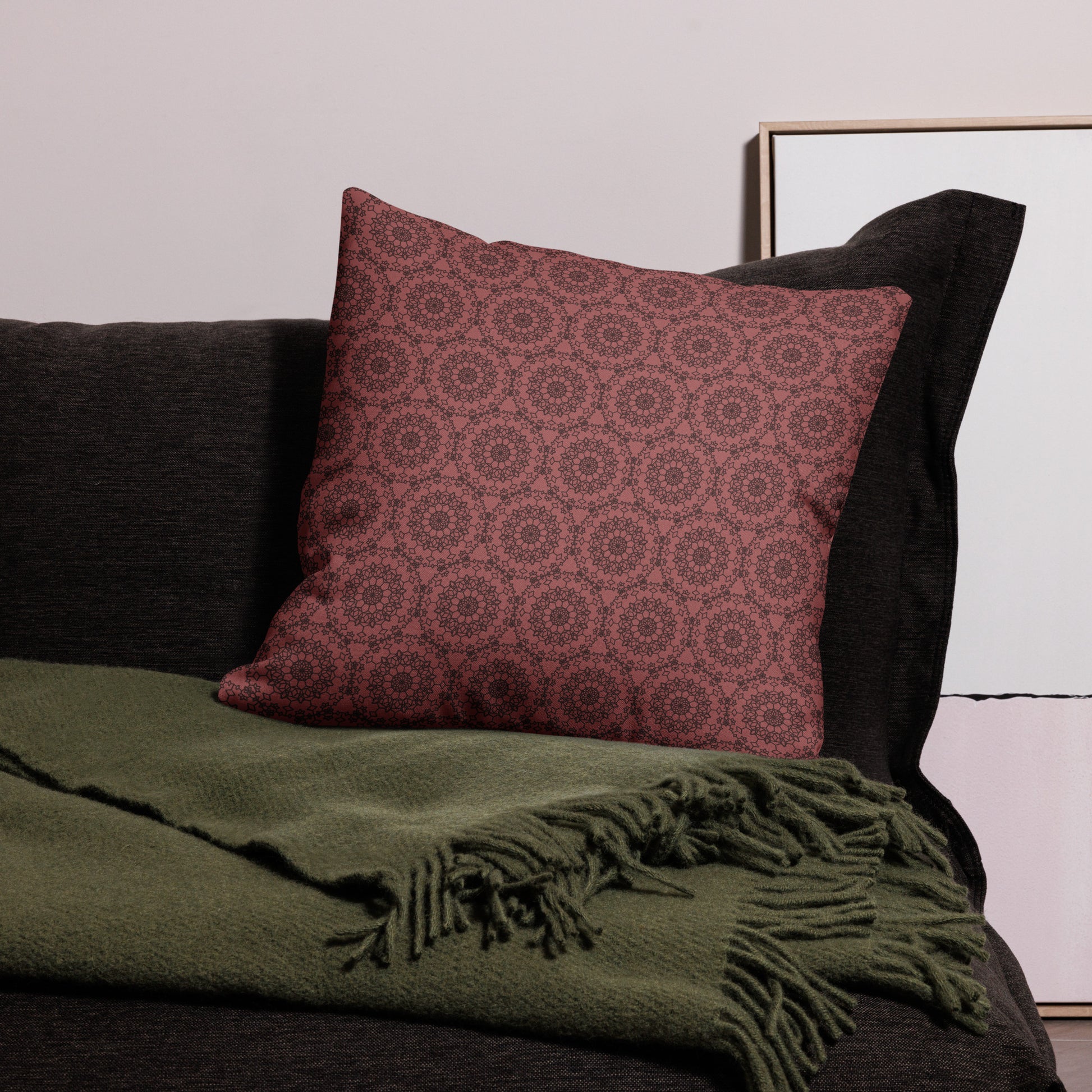 22″×22″ premium throw pillow with the 'Dodecagon' rose geometric pattern on dark sofa with green fringed throw.
