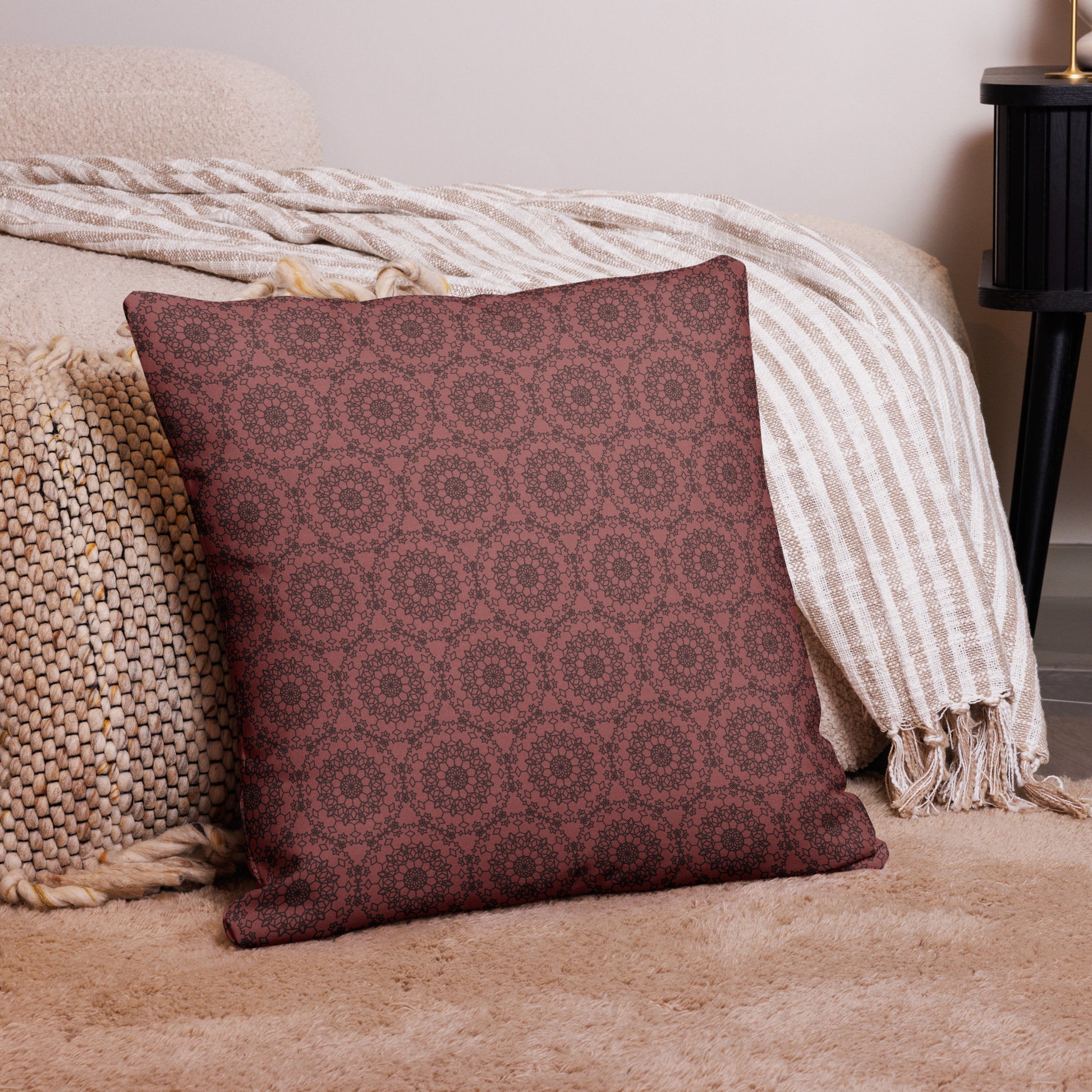 22″×22″ premium throw pillow with the 'Dodecagon' rose geometric pattern on carpet beside bed with striped throw.