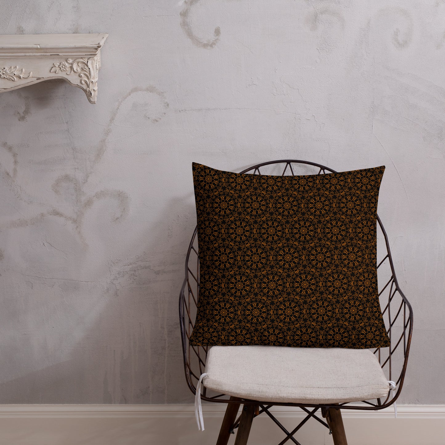 22″×22″ premium throw pillow with the 'Enneagon' black & gold geometric pattern on a wire chair.