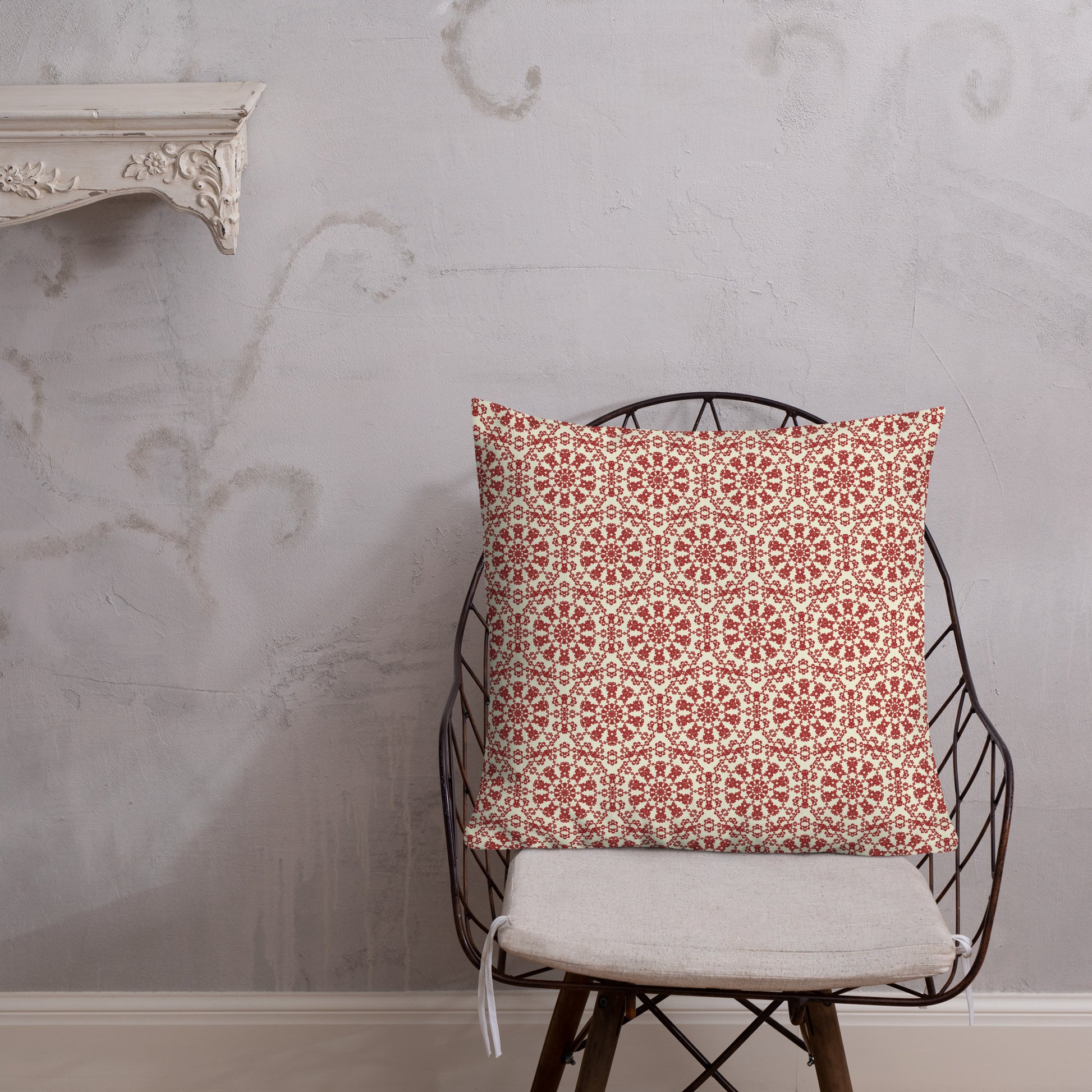 22″×22″ premium throw pillow with the ‘Decagon’ terracotta and beige geometric pattern on a wire chair against an ornate plaster wall.