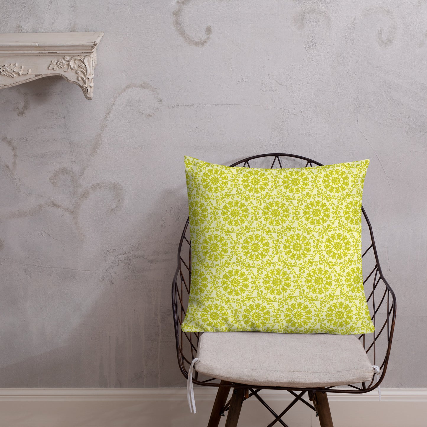 22″×22″ premium throw pillow with the 'Hendecagon' yellow-green geometric pattern on a wire chair with white plaster wall
