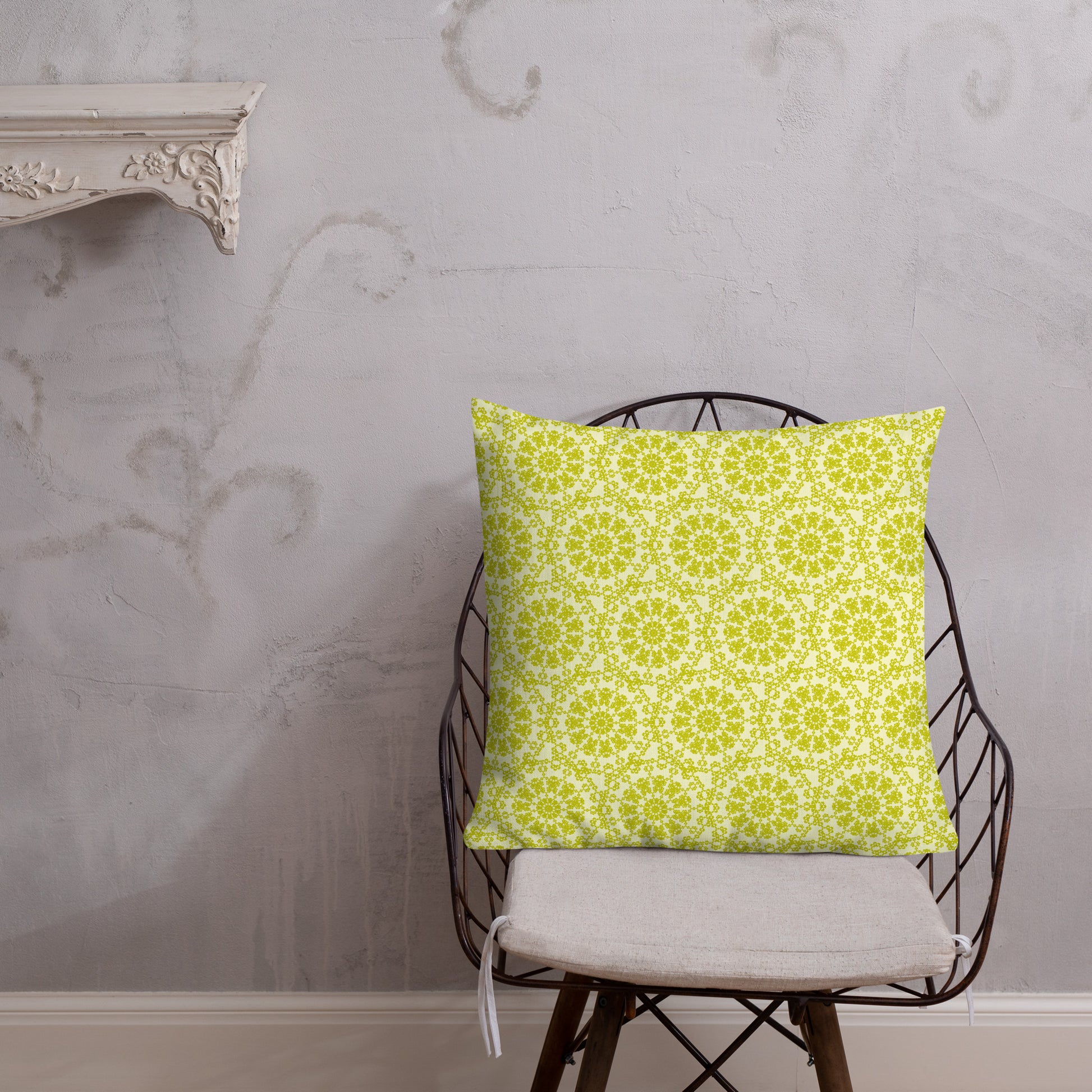 22″×22″ premium throw pillow with the 'Hendecagon' yellow-green geometric pattern on a wire chair with white plaster wall