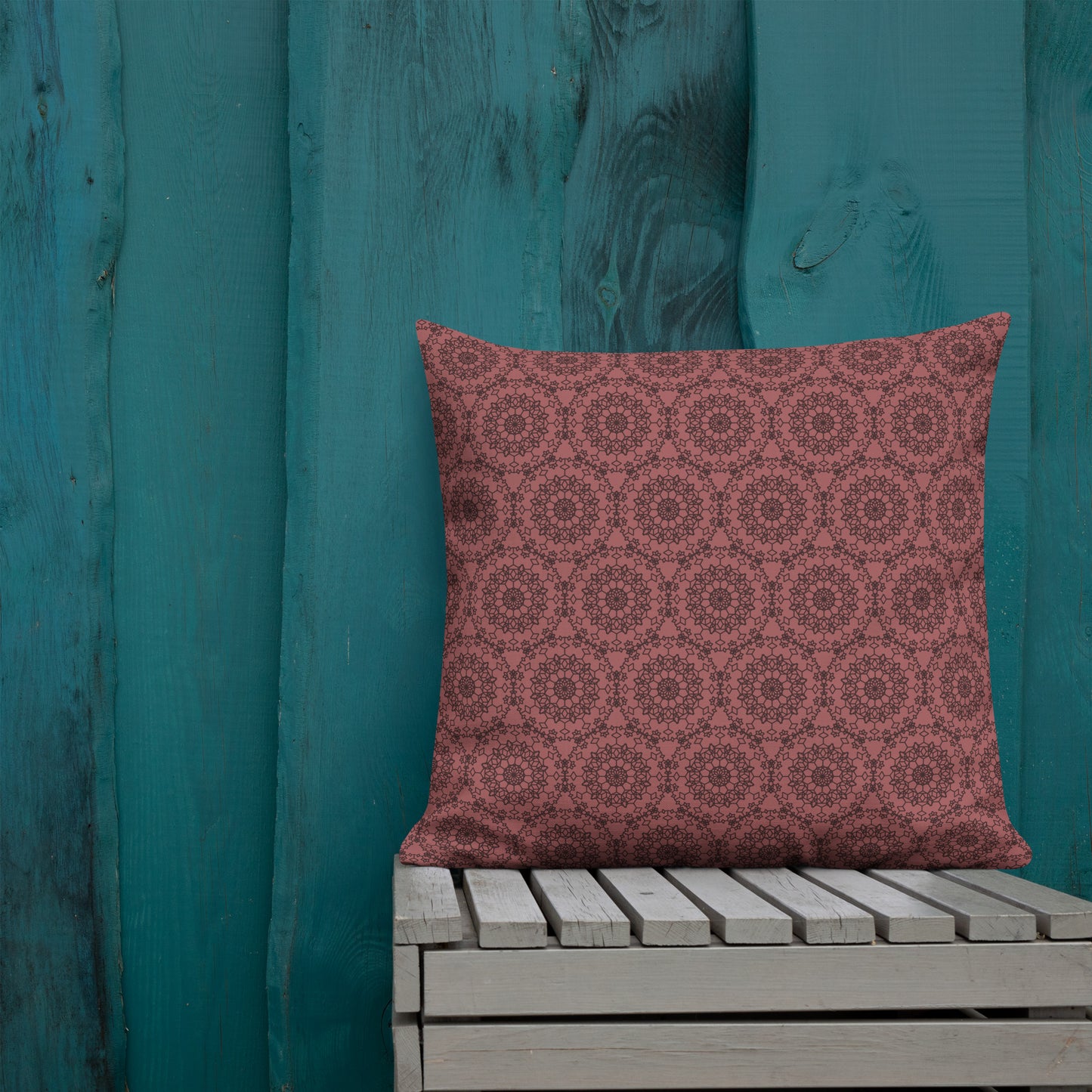 22″×22″ premium throw pillow with the 'Dodecagon' rose geometric pattern on wooden bench against teal painted wall.