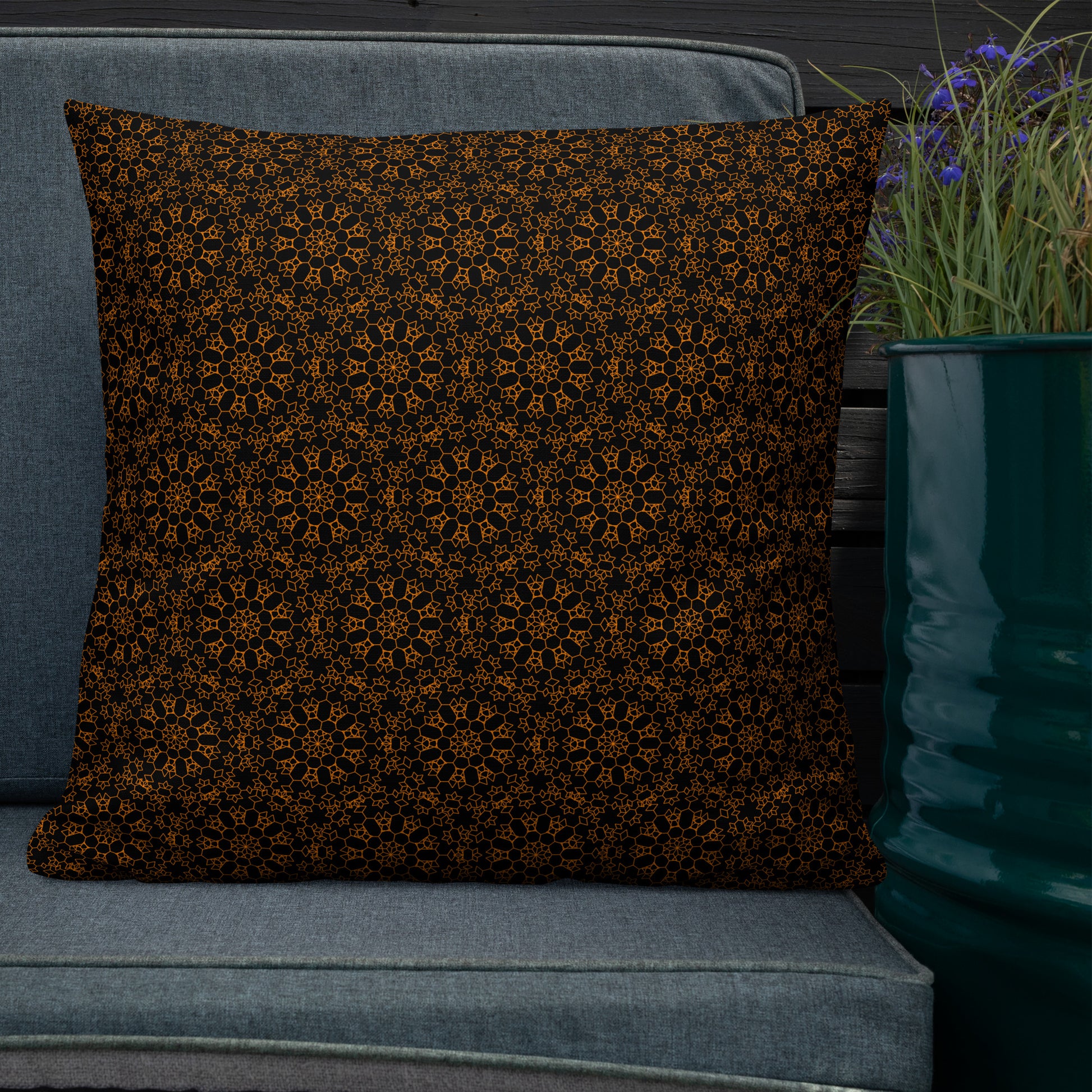22″×22″ premium throw pillow with the 'Enneagon' black & gold geometric pattern on an outdoor sofa with dark slat wall.