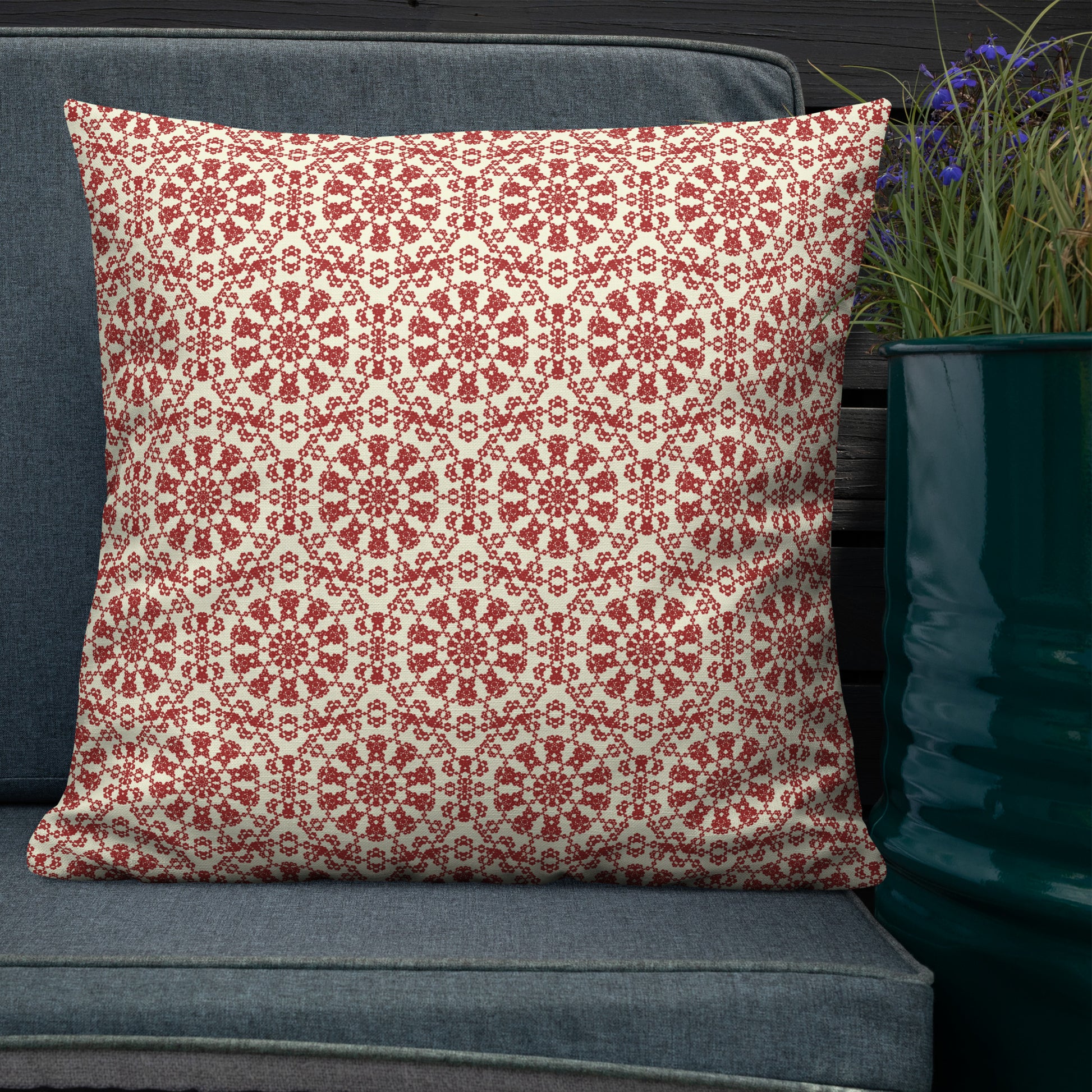 22″×22″ premium throw pillow with the ‘Decagon’ terracotta and beige geometric pattern on a dark teal sofa with blue flowers.